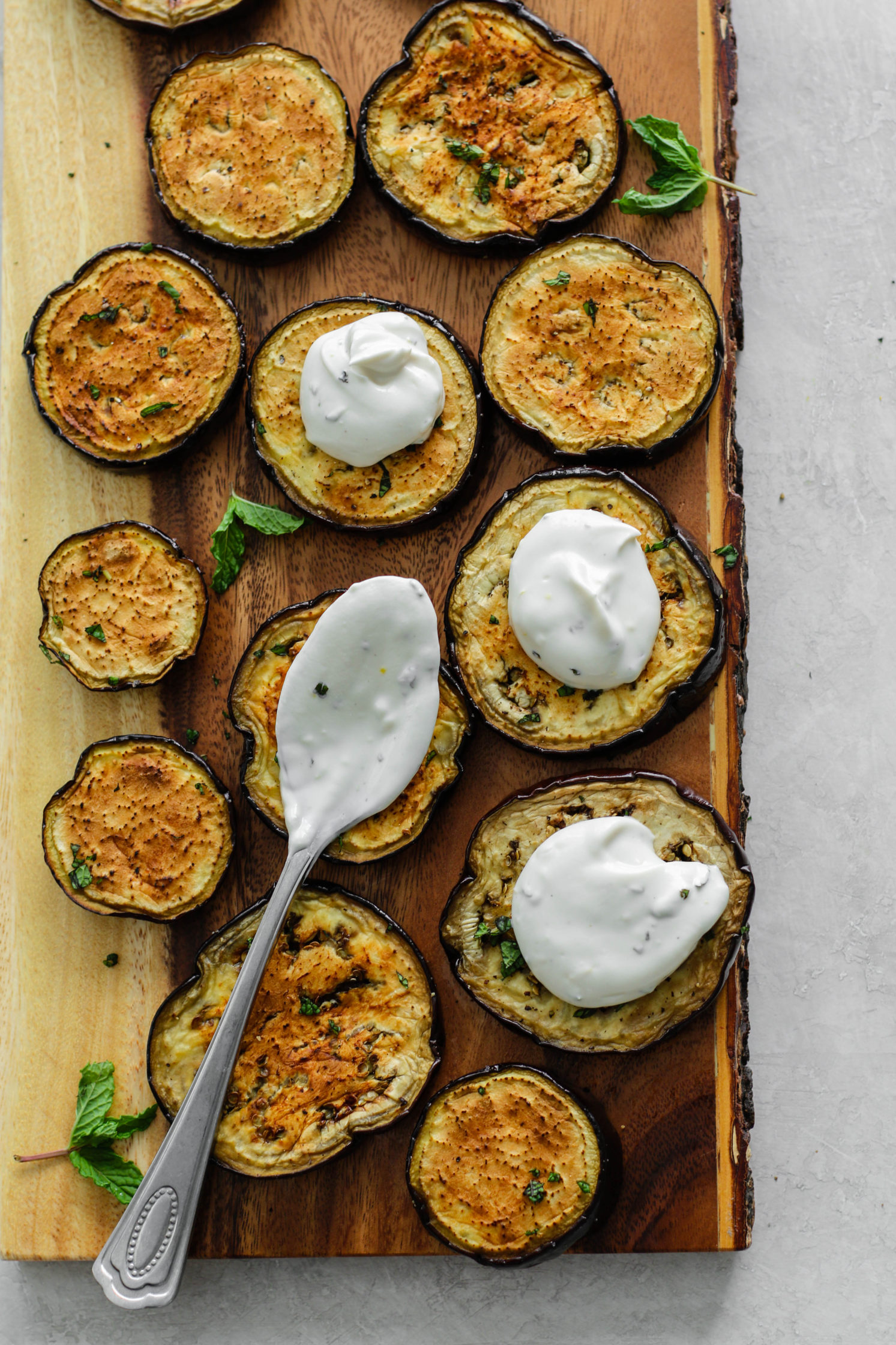 Eggplant Rounds topped with Herbed Yogurt Sauce and a spoon by Flora & Vino
