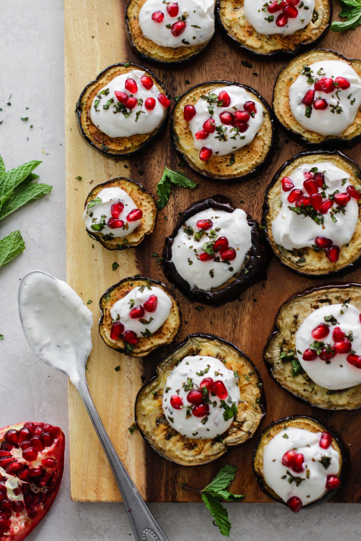 Eggplant Rounds with Herbed Yogurt on wooden board with yogurt spoon by Flora & Vino