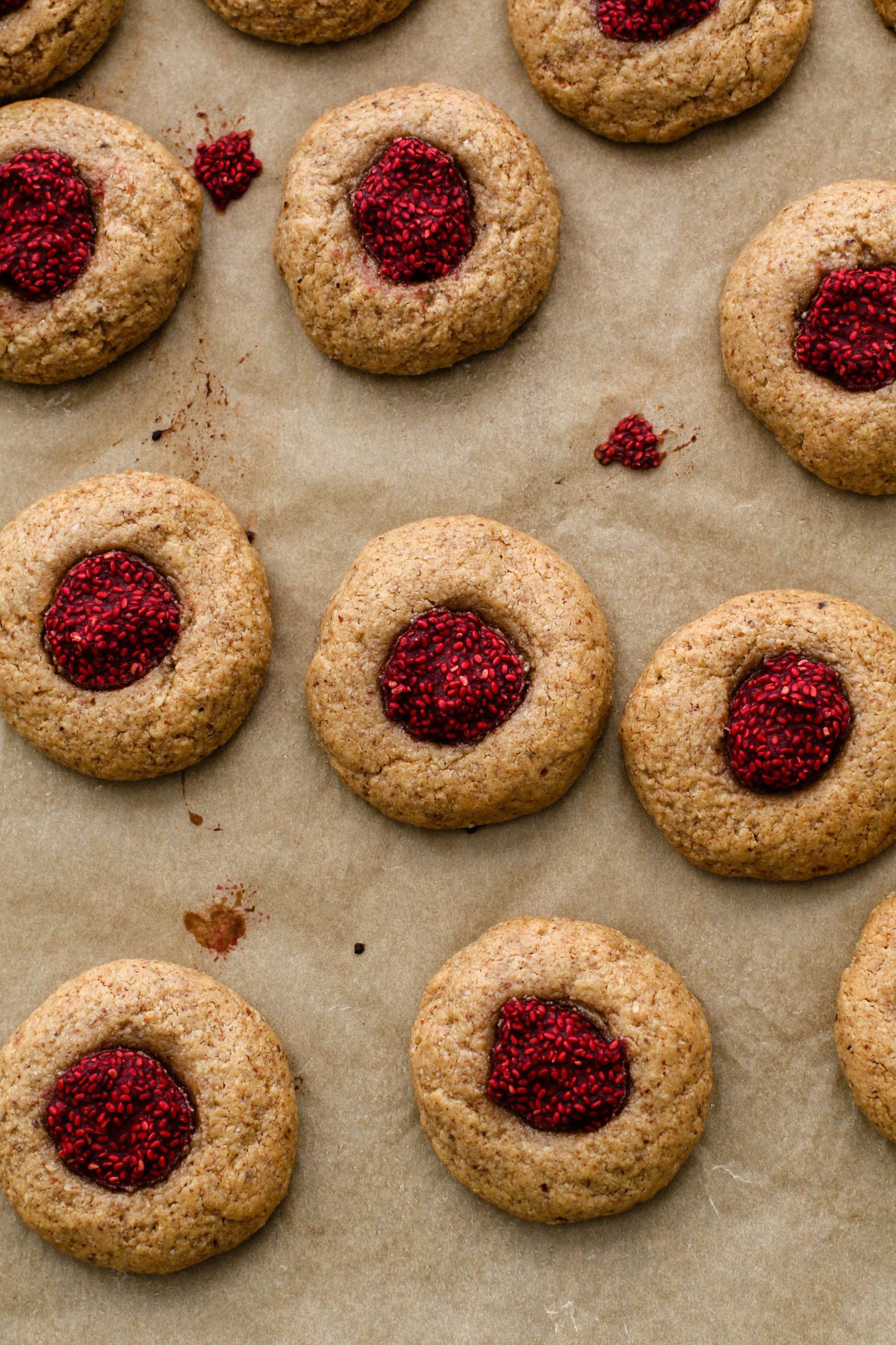 Raspberry-Beet Almond Flour Thumbprint Cookies baked on parchment lined baking sheet by Flora & Vino