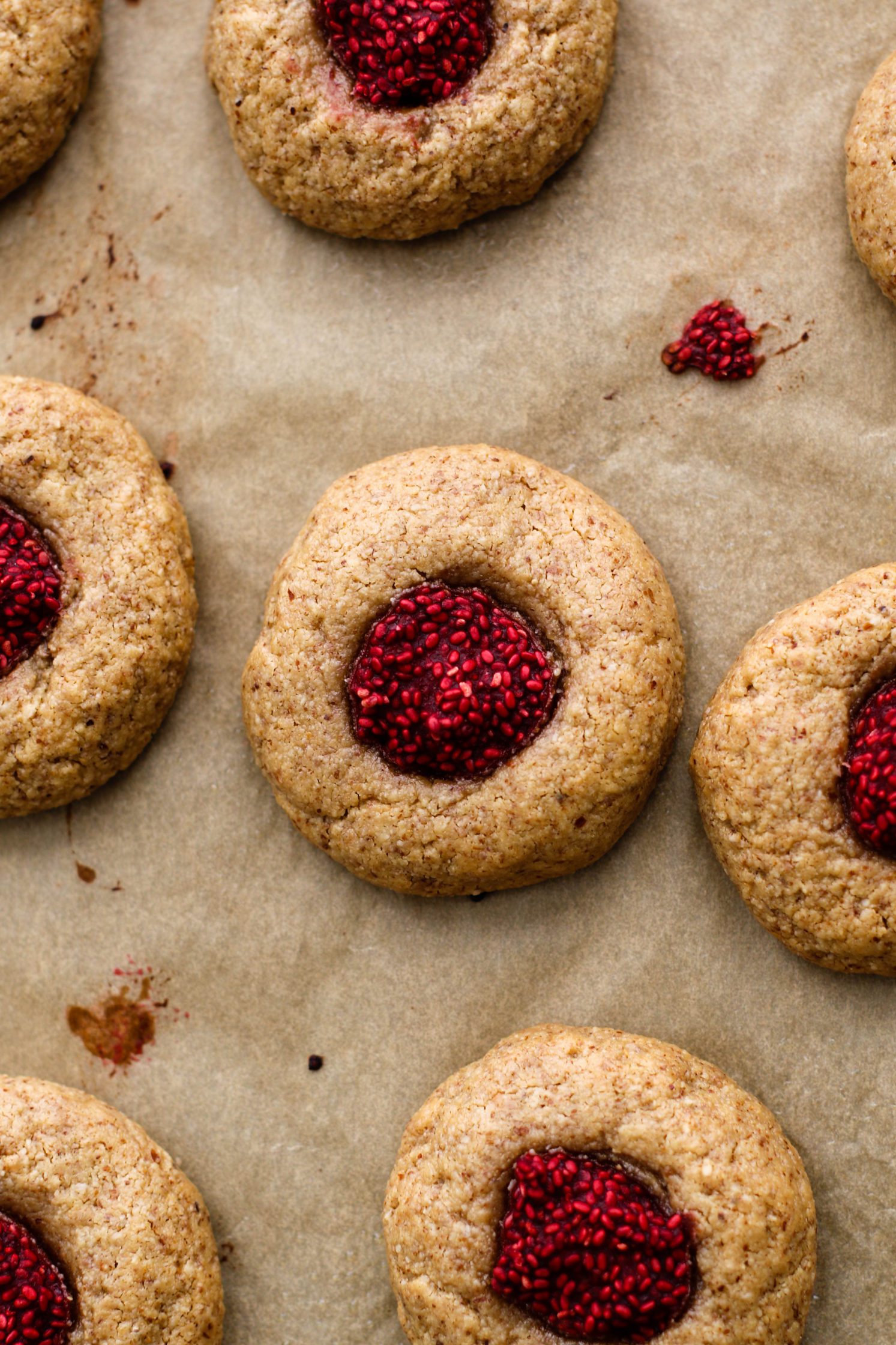Raspberry-Beet Almond Flour Thumbprint Cookies baked on parchment paper by Flora & Vino