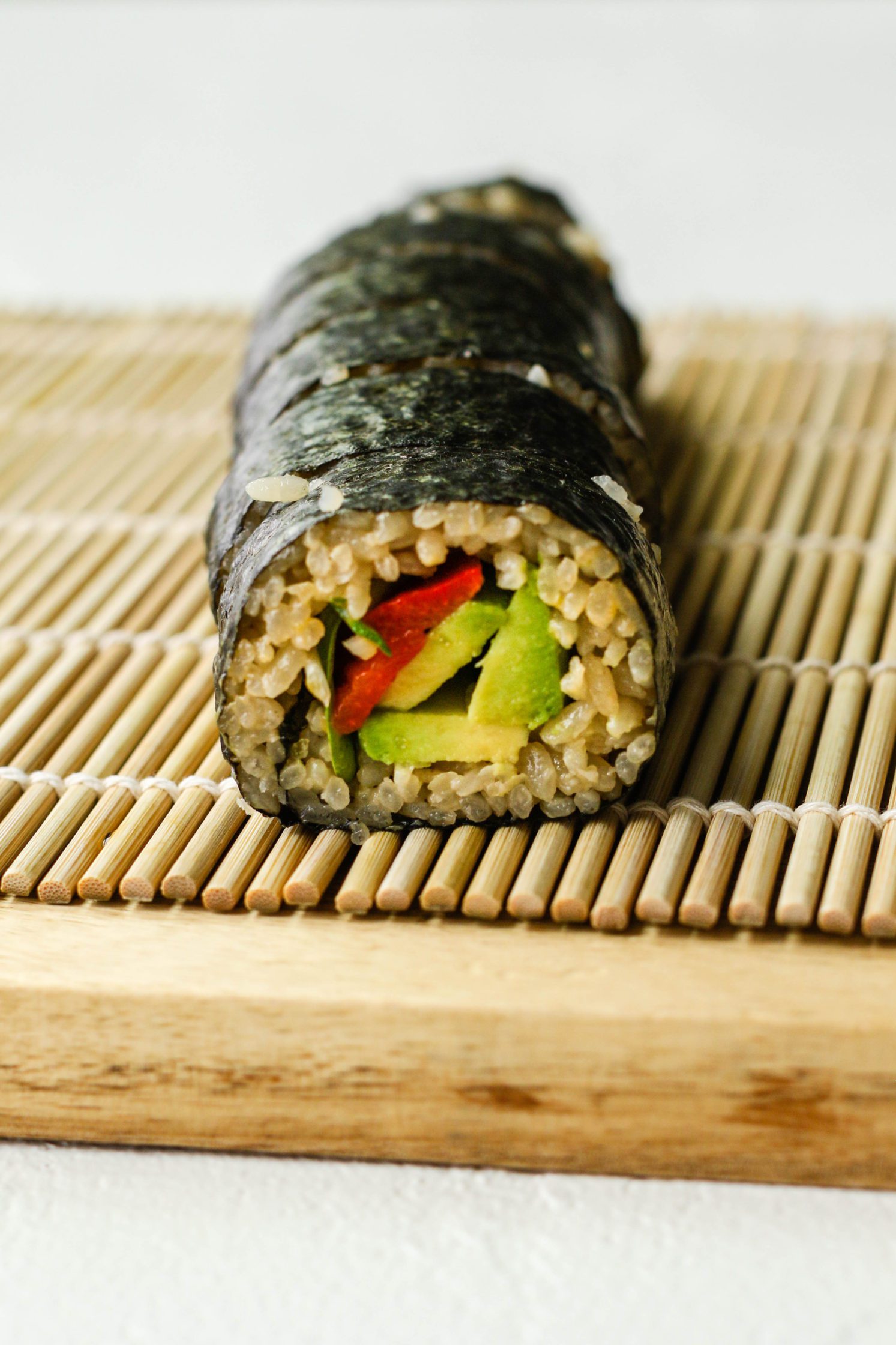 Vegan Avocado & Roasted Red Pepper Sushi on sushi rolling mat by Flora & Vino