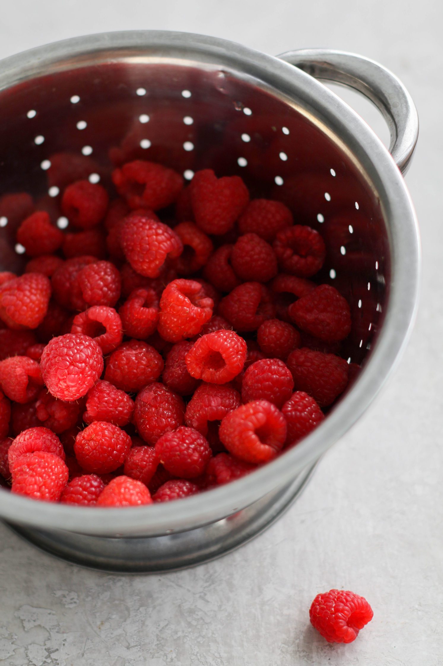 fresh raspberries in colander by Flora & Vino