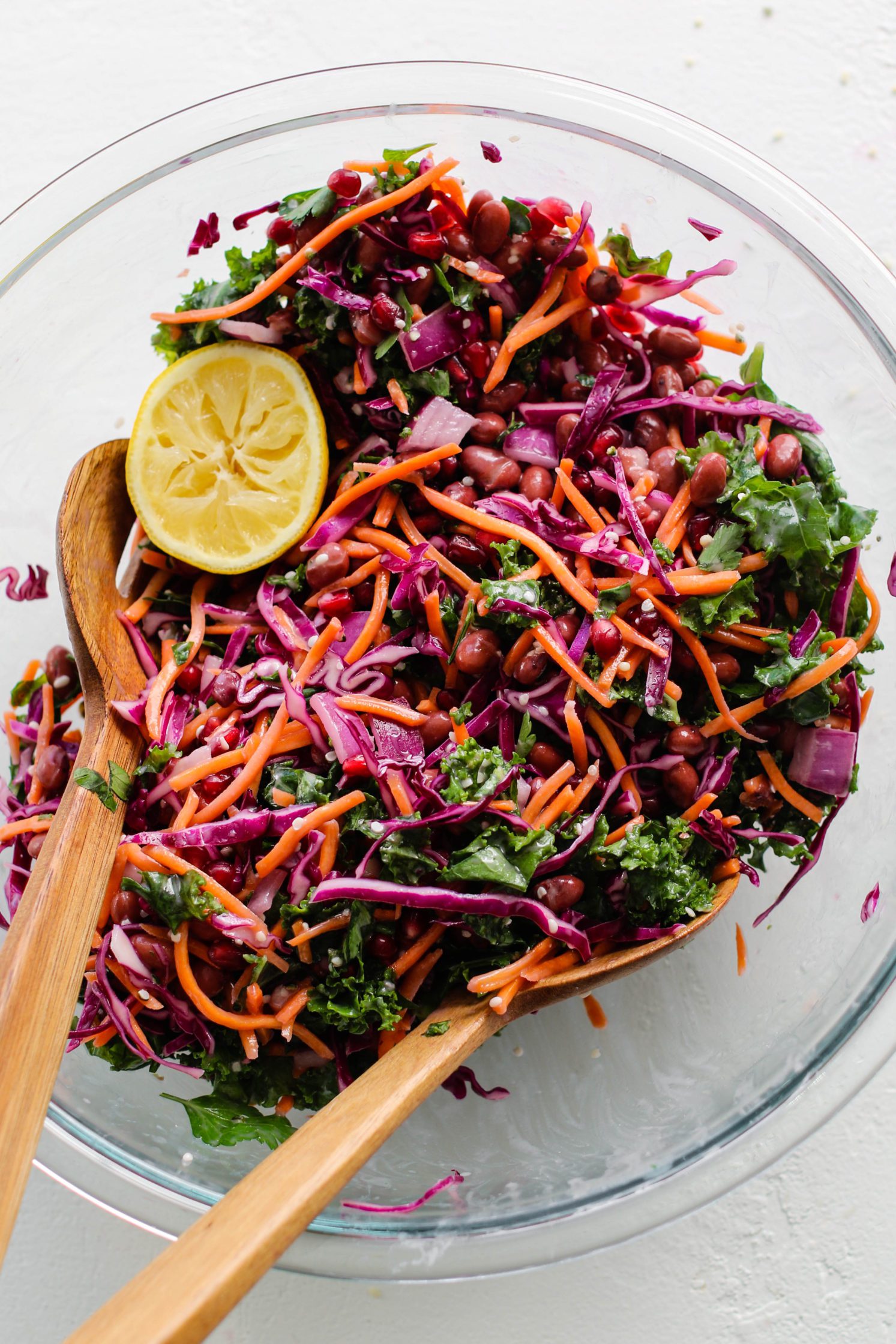 Red Bean & Pomegranate Salad in large glass bowl with two wooden salad forks 