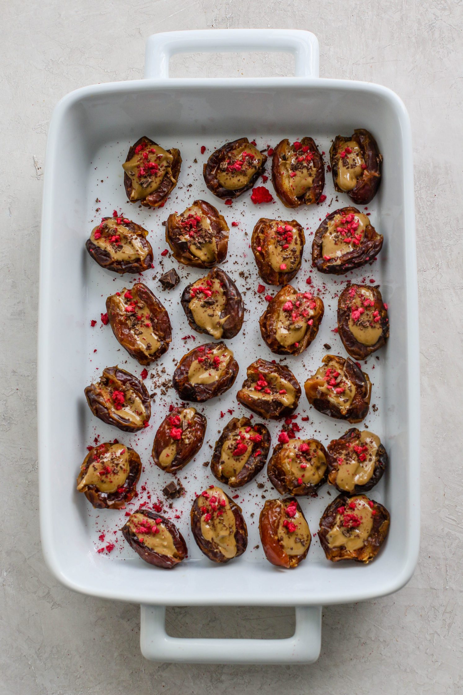 SunButter Stuffed Dates served in white baking dish topped with freeze-dried raspberries by Flora & Vino 