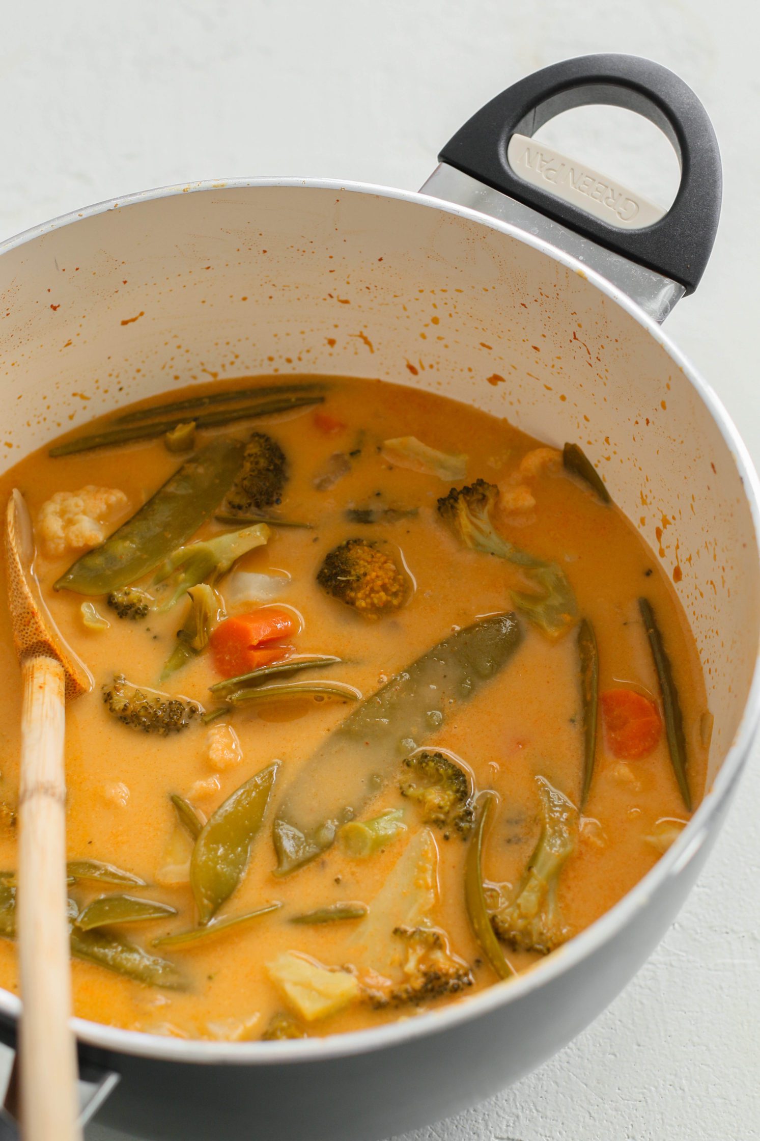 The Quickest Vegan Curry in a pot with a wooden spoon by Flora & Vino