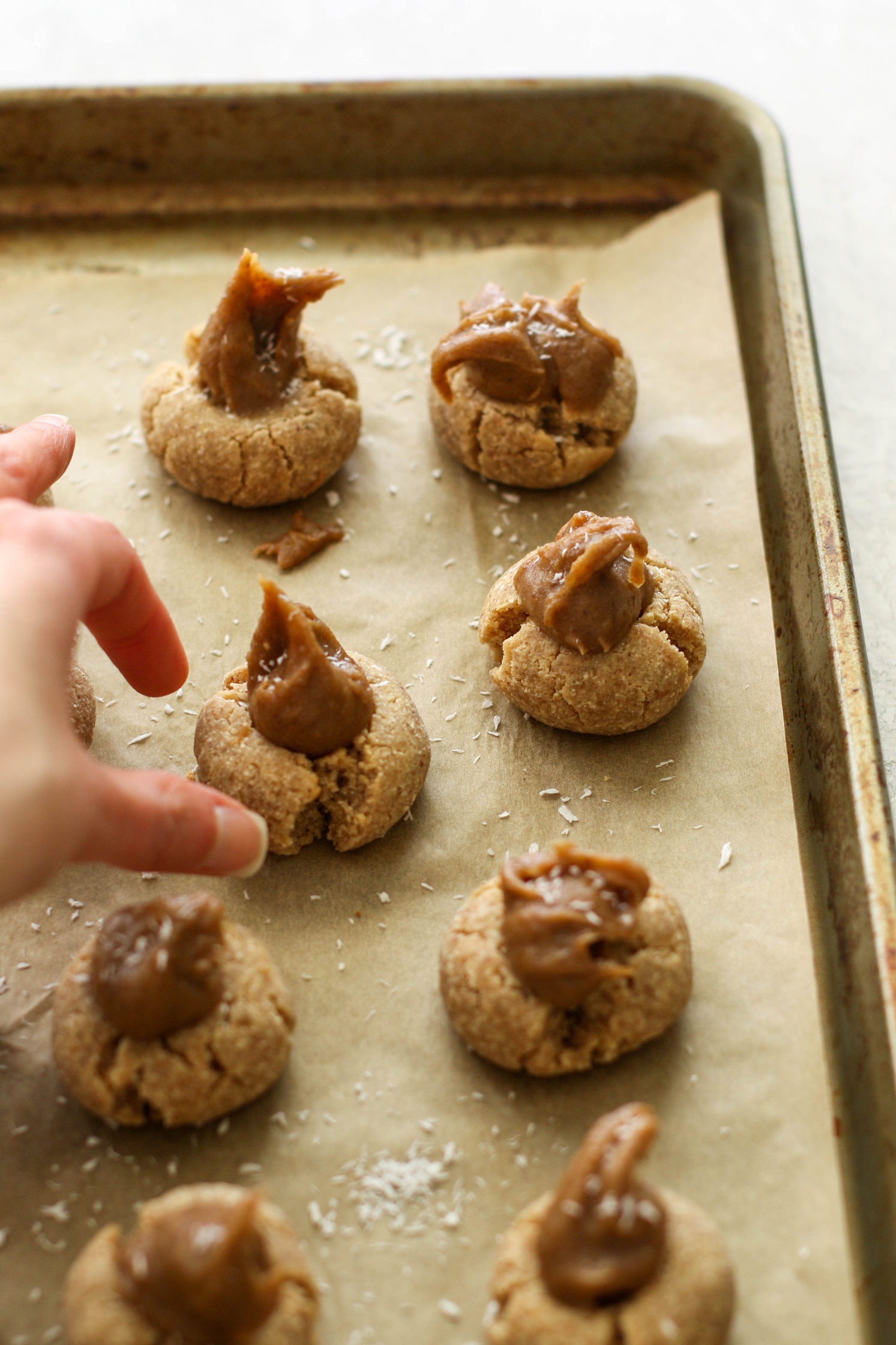 hand reaching for Coconut Caramel Thumbprint Cookies by Flora & Vino 