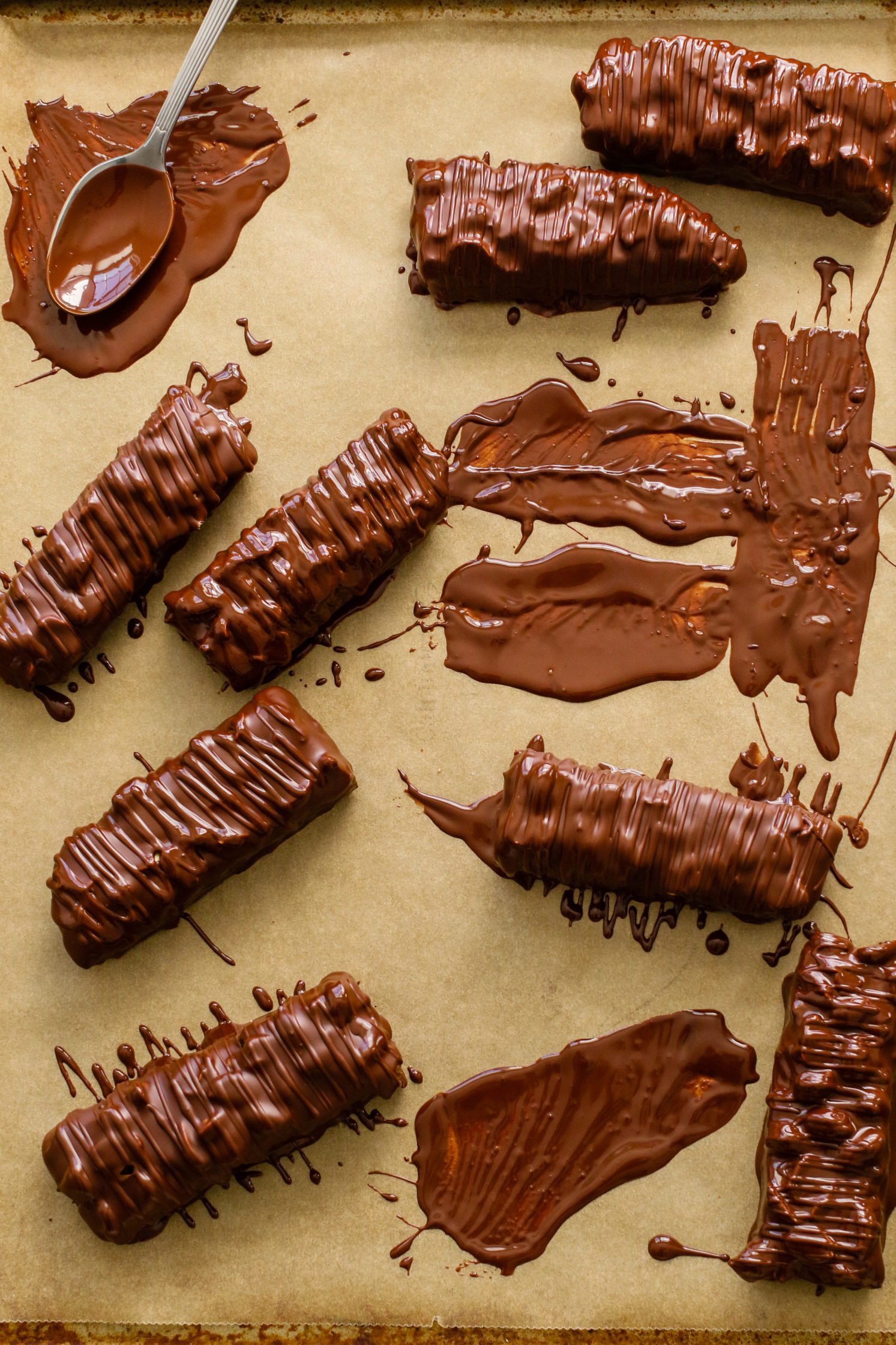 Vegan Salted Snickers Bars dipped in melted chocolate on parchment paper by Flora & Vino 