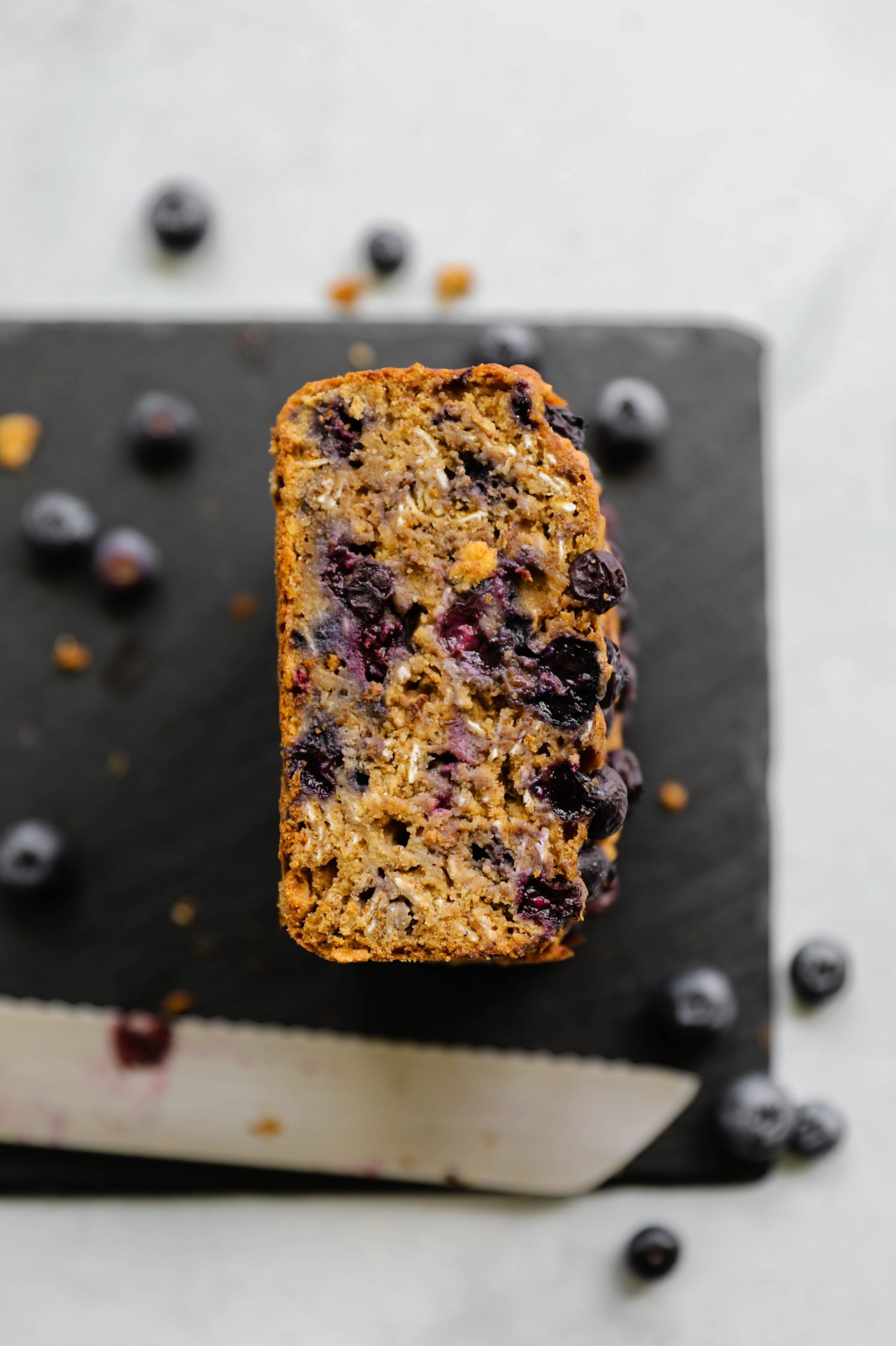 Blueberry Banana Breakfast Bread tacked on serving board with knife by Flora & Vino
