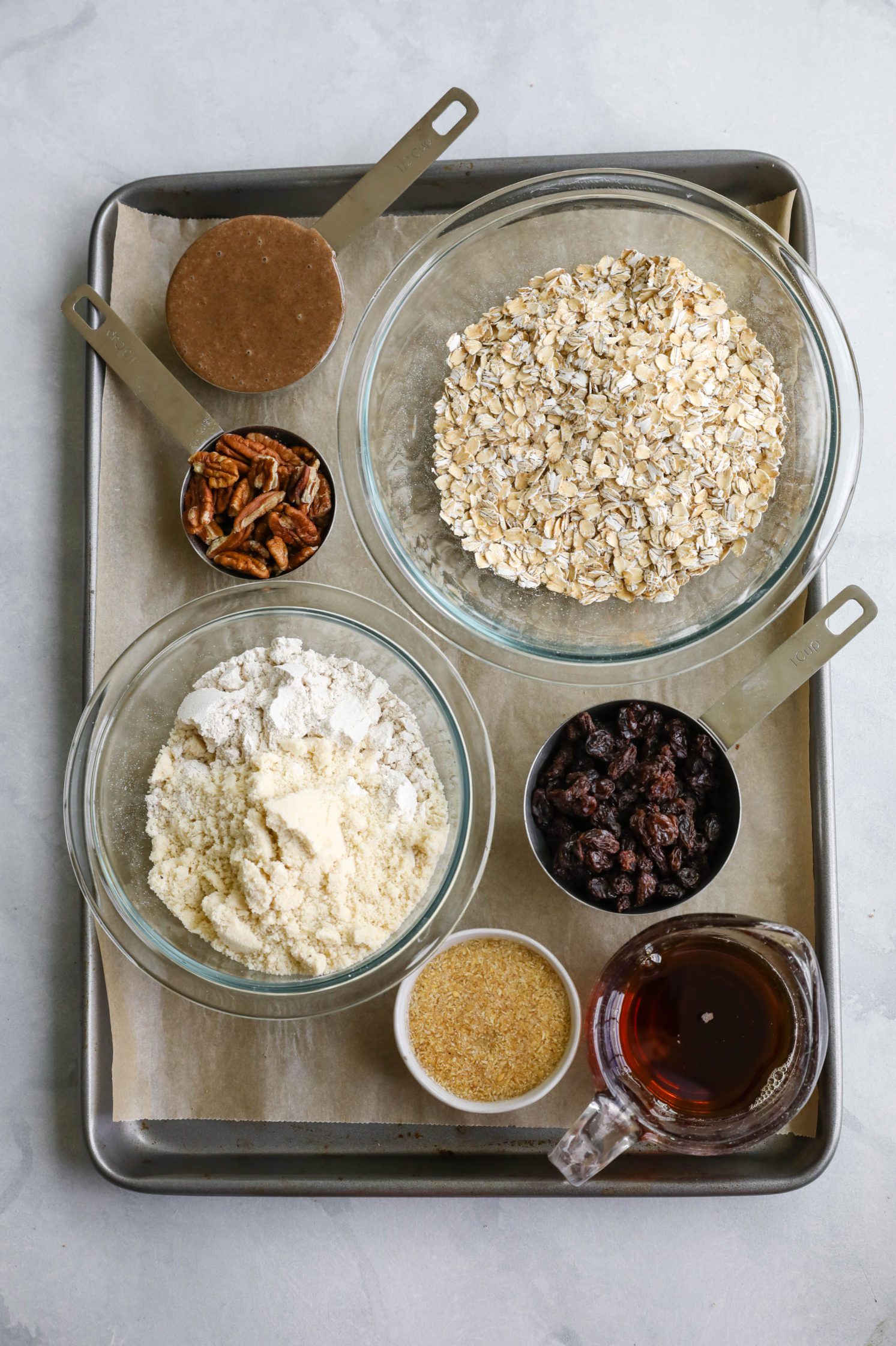 Oatmeal Raisin Pecan Cookie Ingredients on parchment lined baking sheet by Flora & Vino