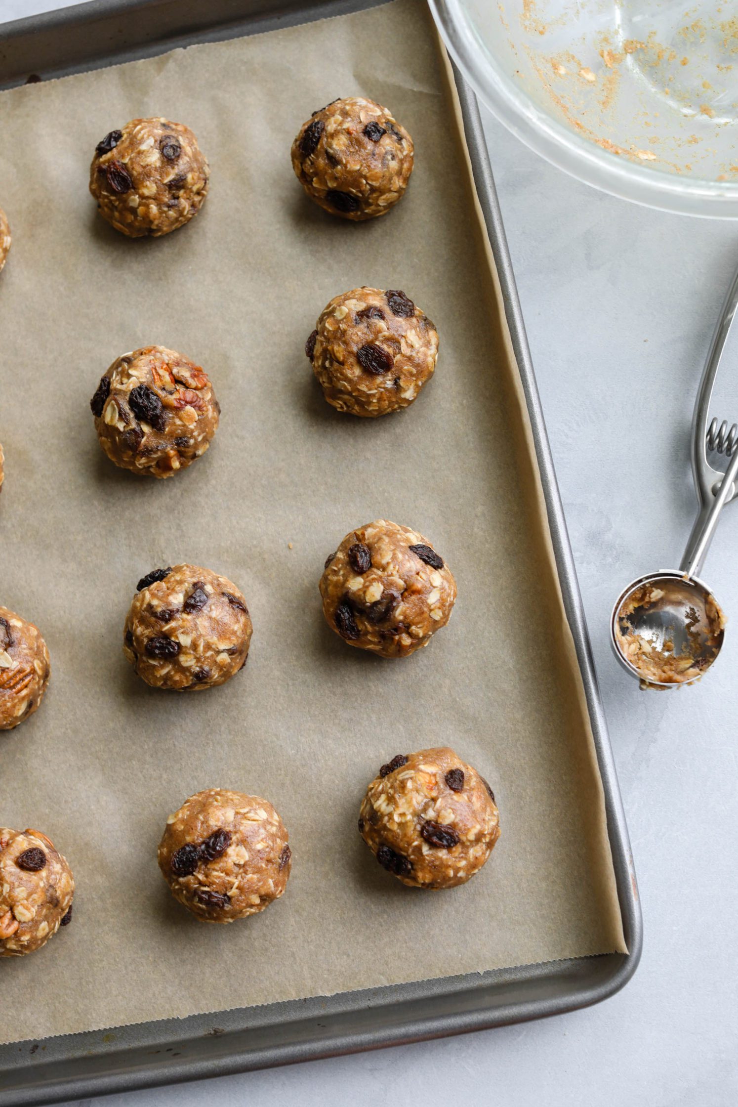 Oatmeal Raisin Pecan Cookies rolled into balls on parchment lined baking sheet by Flora & Vino
