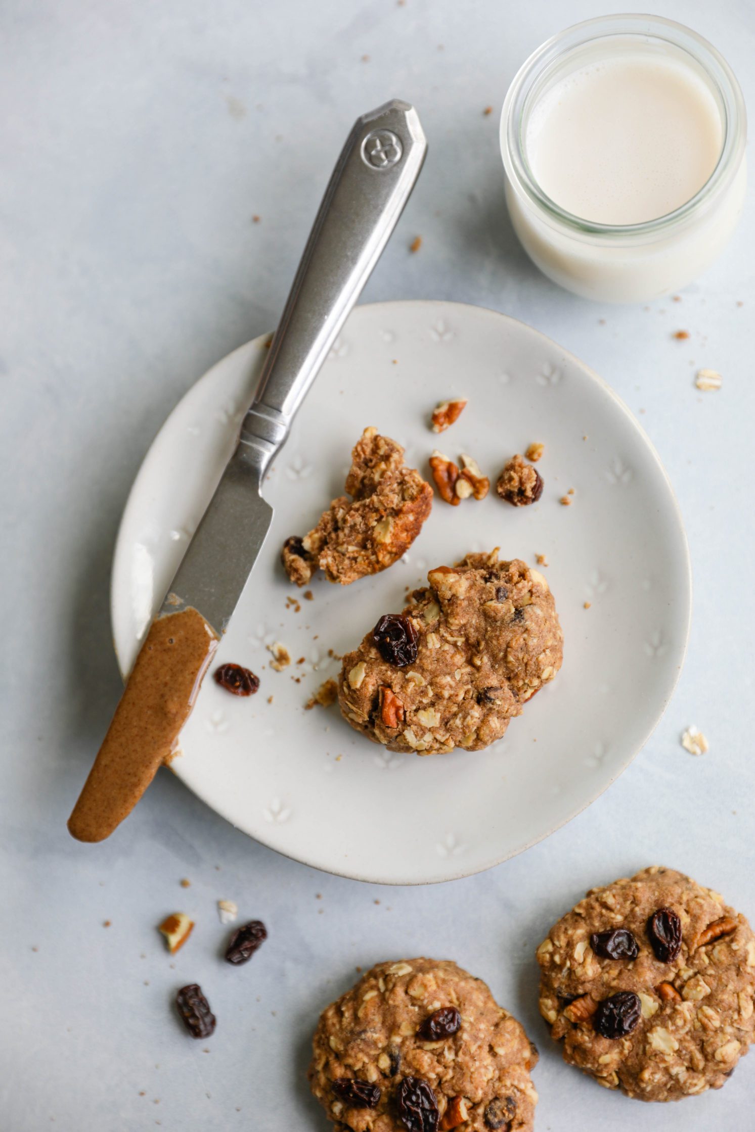 Oatmeal Raisin Pecan Cookies in pieces on plates with almond milk by Flora & Vino 