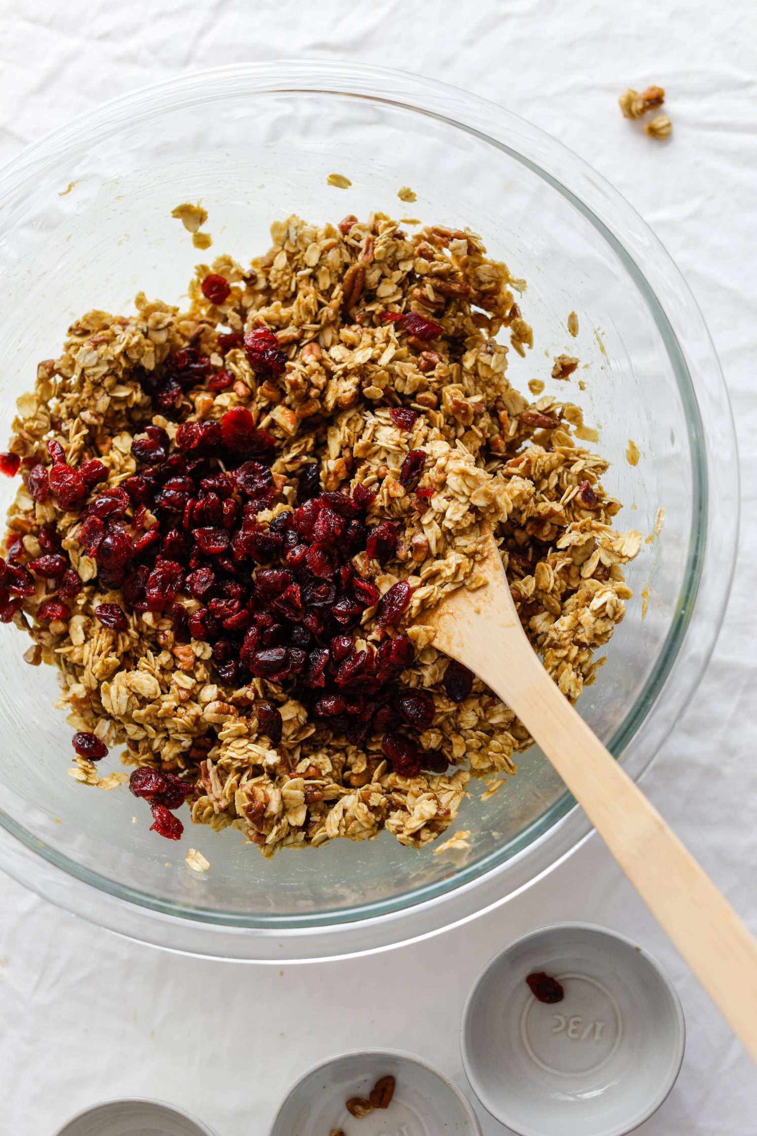 Apple Cranberry Pecan Granola mixed in glass bowl with wooden spoon 