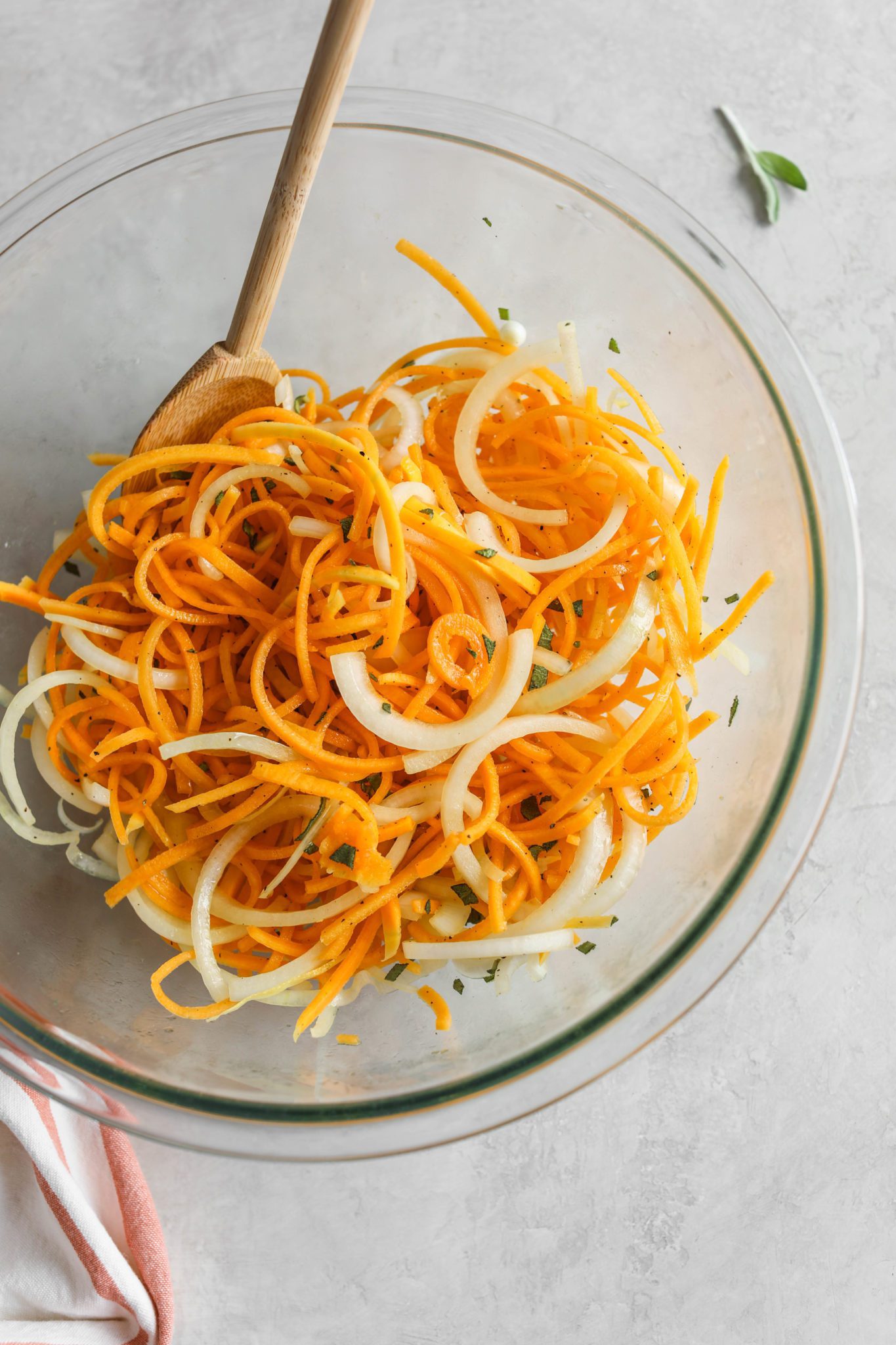 butternut squash noodles with onion in clear bowl and spatula by Flora & Vino
