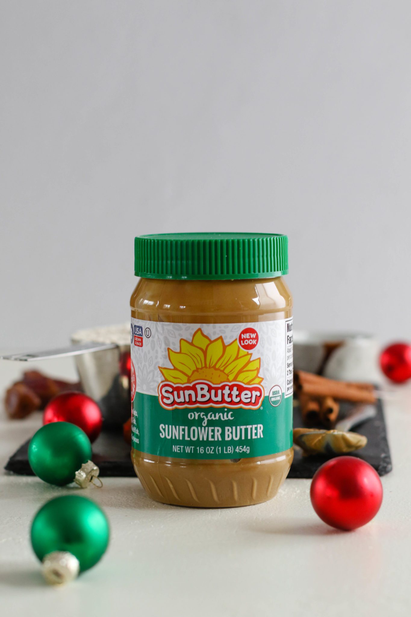 Organic SunButter surrounded by Christmas ornaments by Flora & Vino