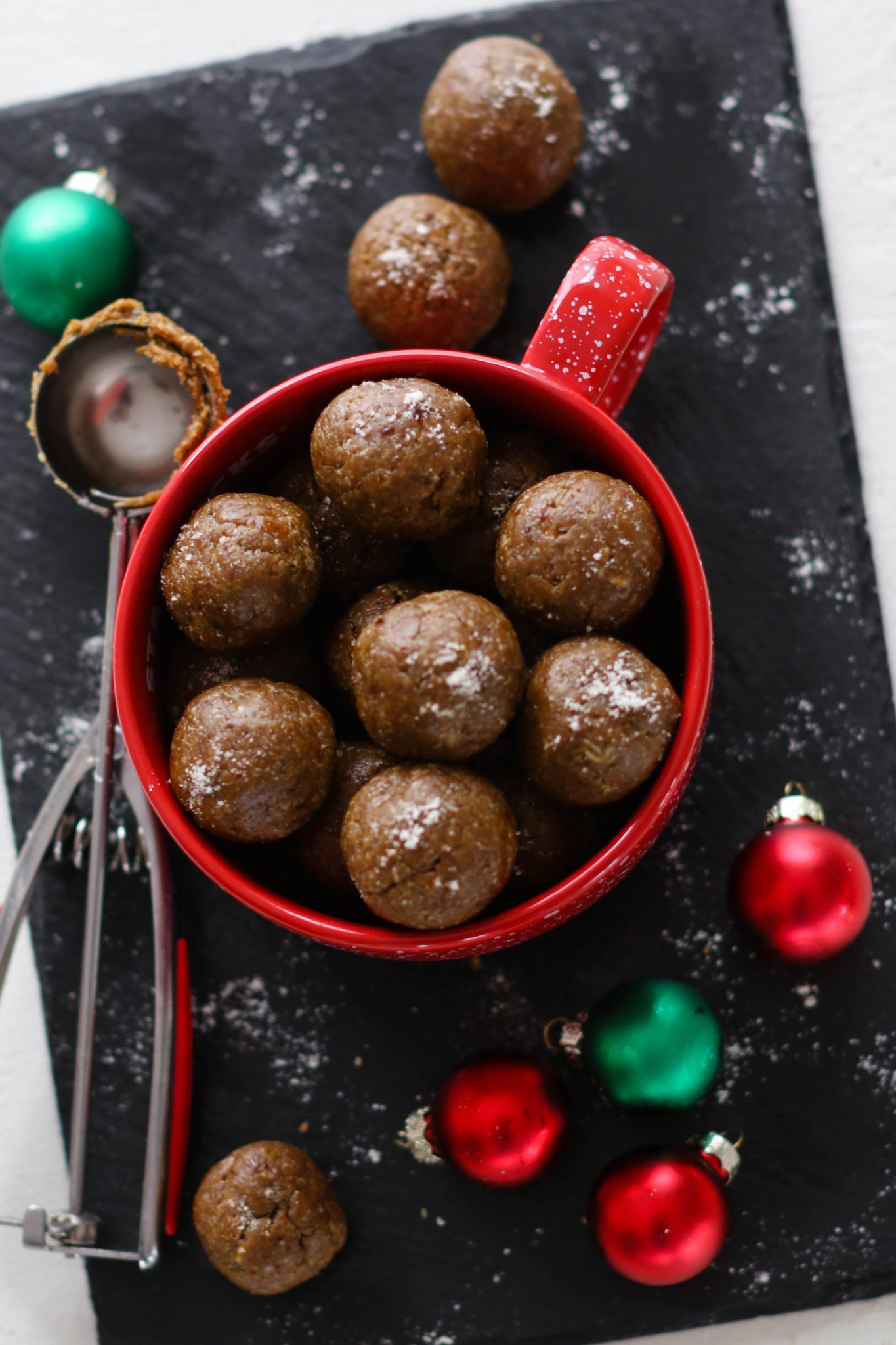 Gingerbread Bliss Balls served in a red mug surrounded by ornaments by Flora & Vino