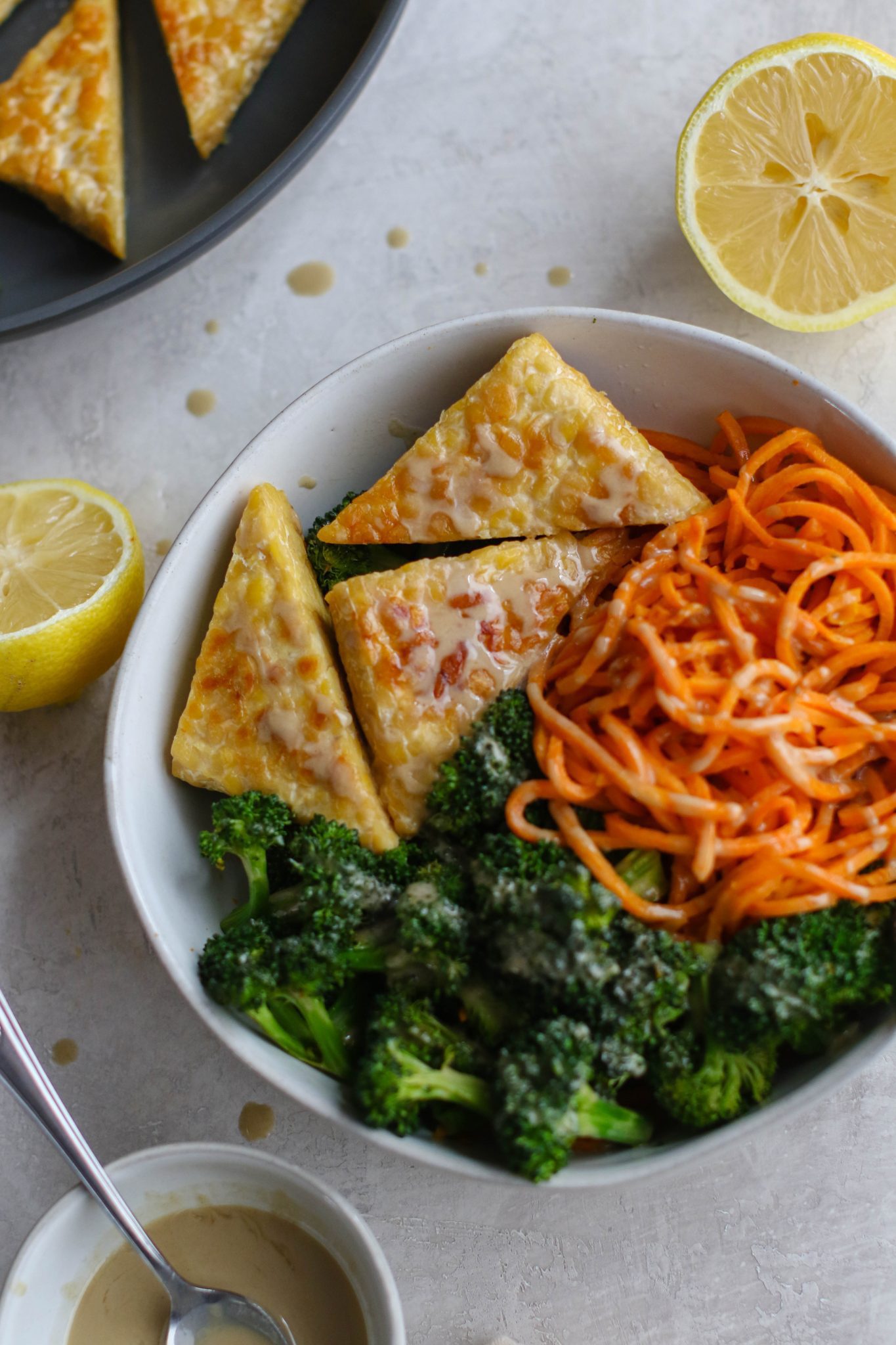 Tahini Tempeh & Sweet Potato Noodle Bowl served in bowl with lemon and tahini by Flora & Vino