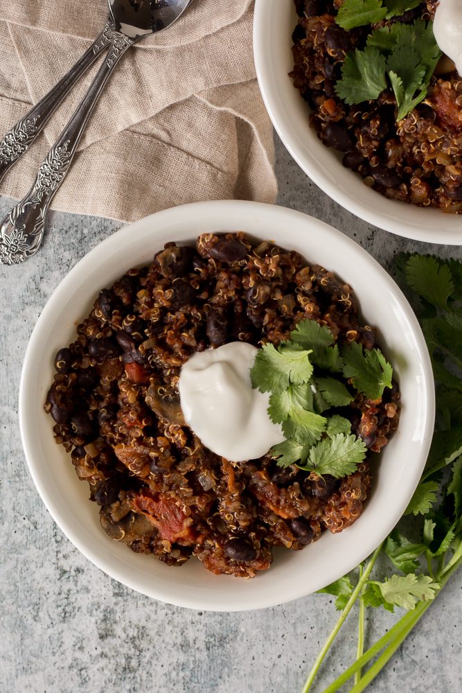 Black Bean Quinoa Chili served in a bowl topped with yogurt and cilantro by Flora & Vino 