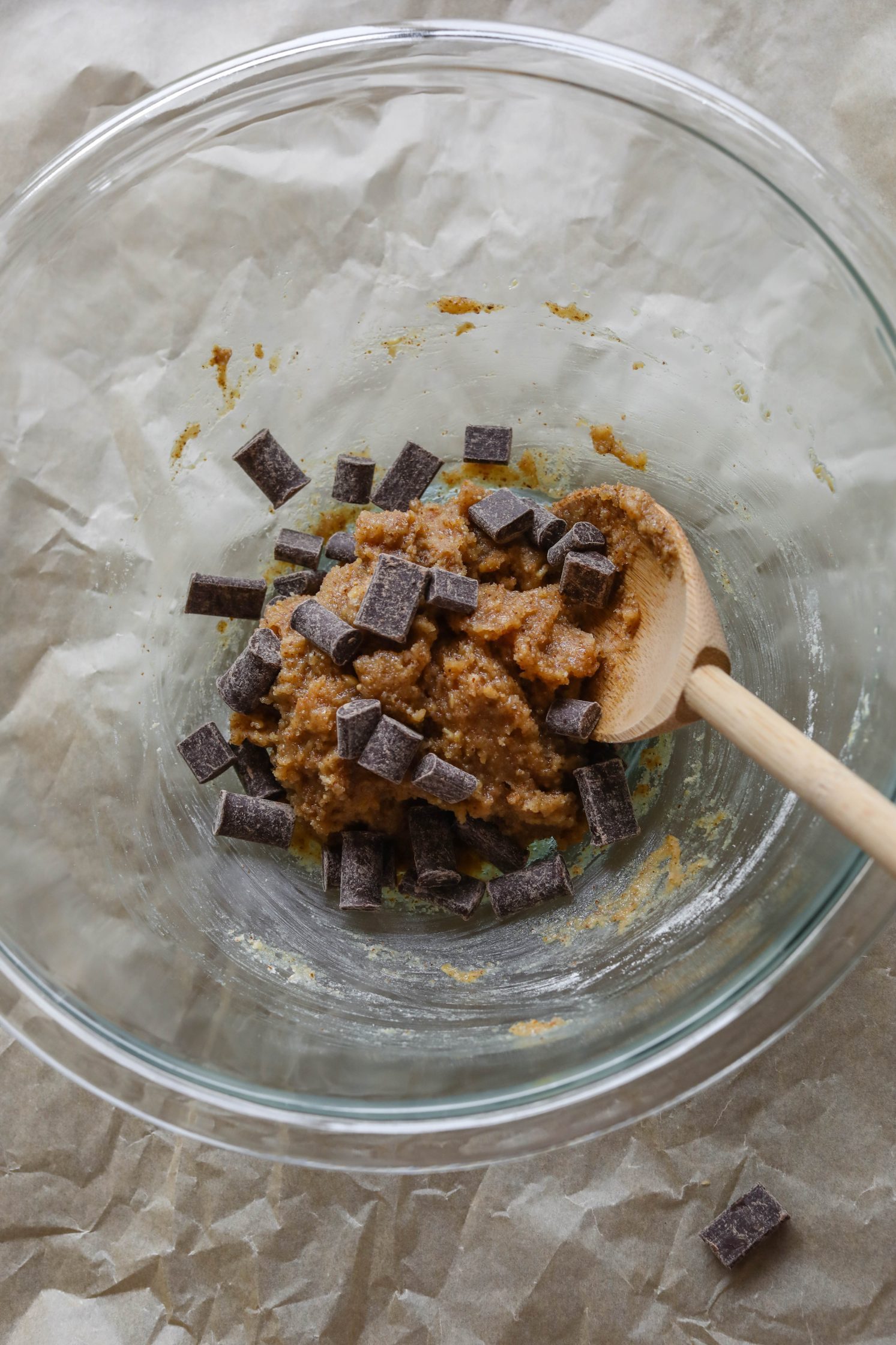 cookie batter with chocolate chunks mixed in with wooden spoon by Flora & Vino