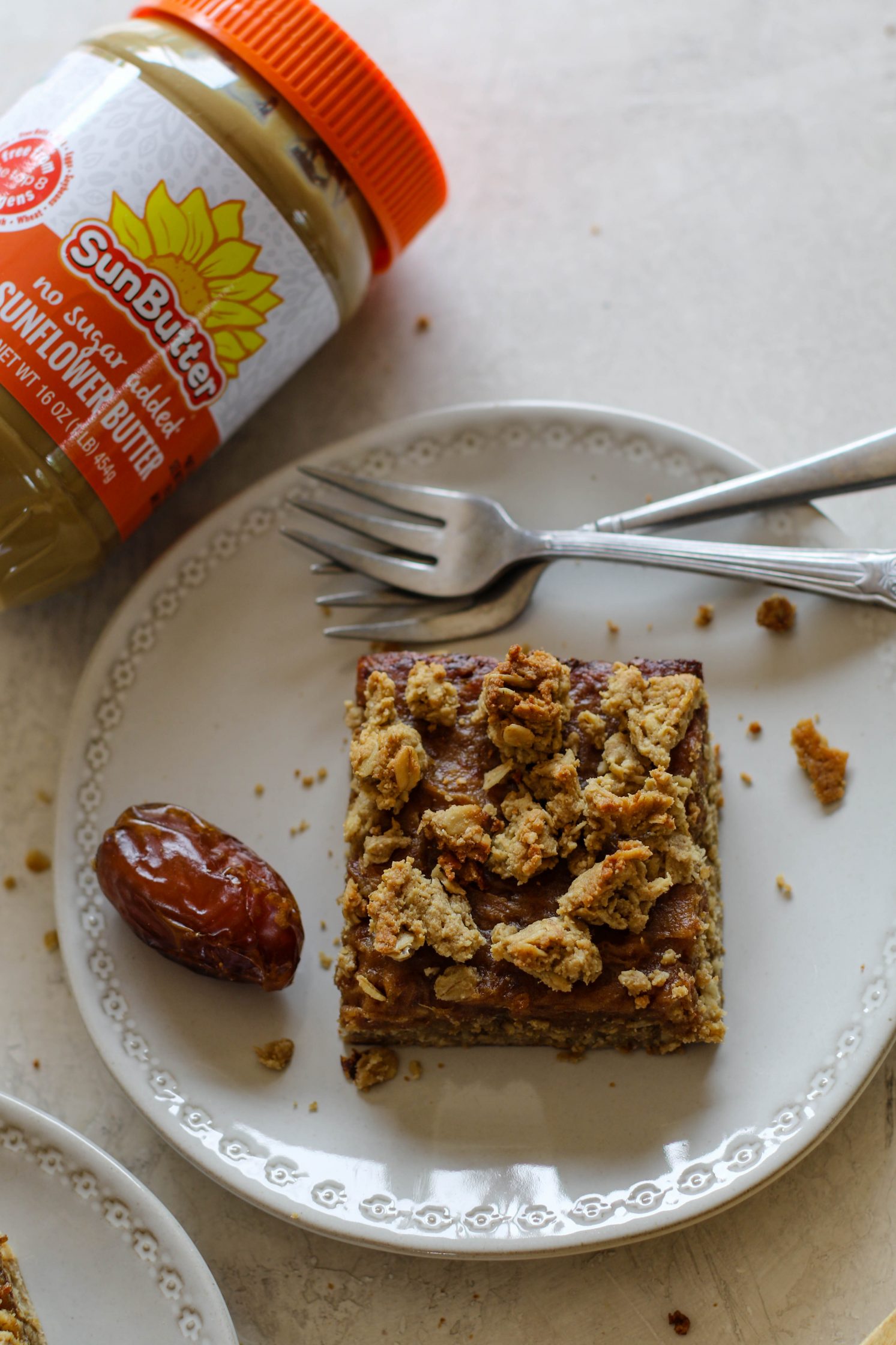 SunButter Date Squares served on a plate with SunButter jar and forks by Flora & Vino