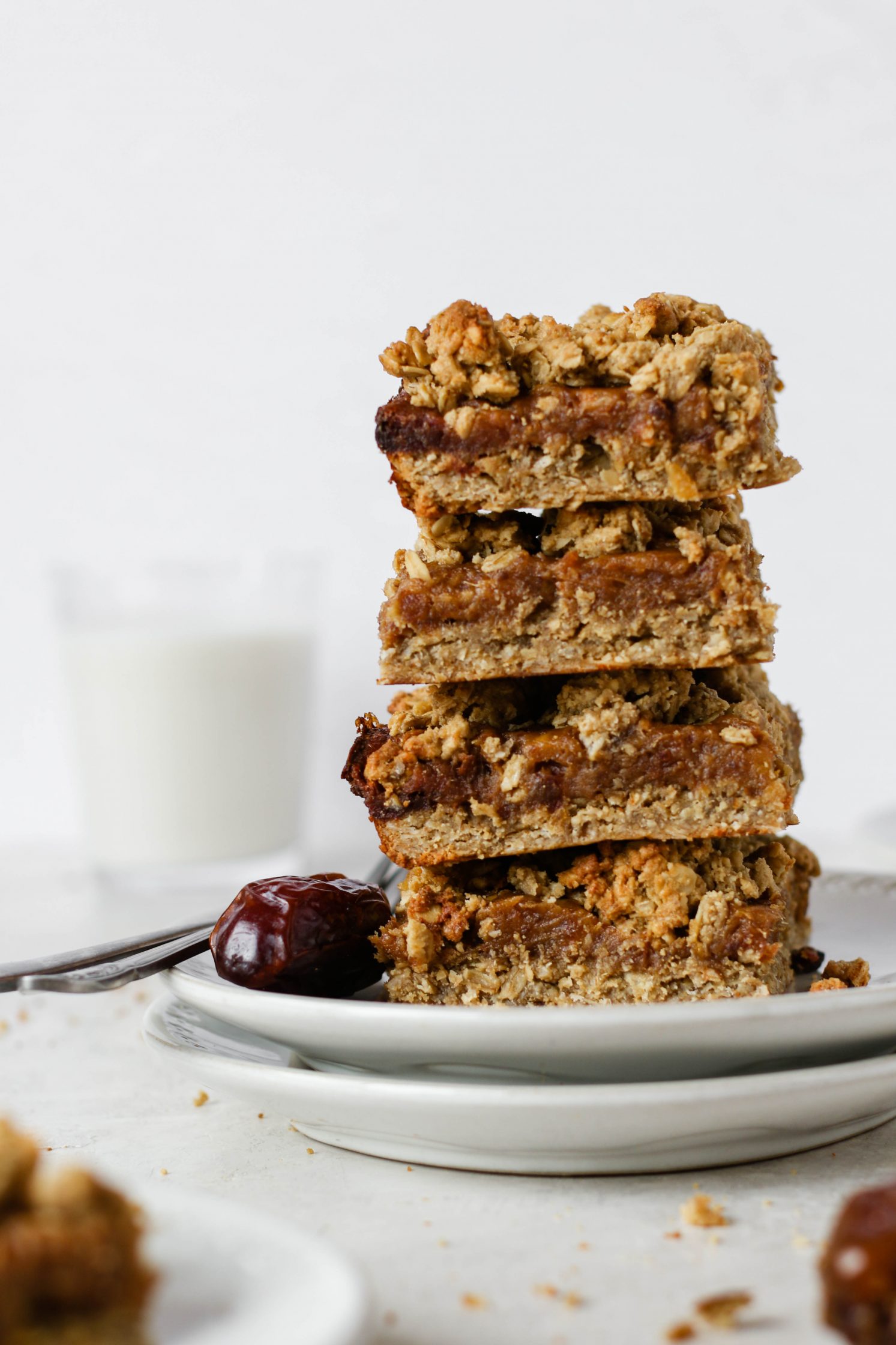 SunButter Date Squares stacked on a plate with a glass of milk behind it by Flora & Vino