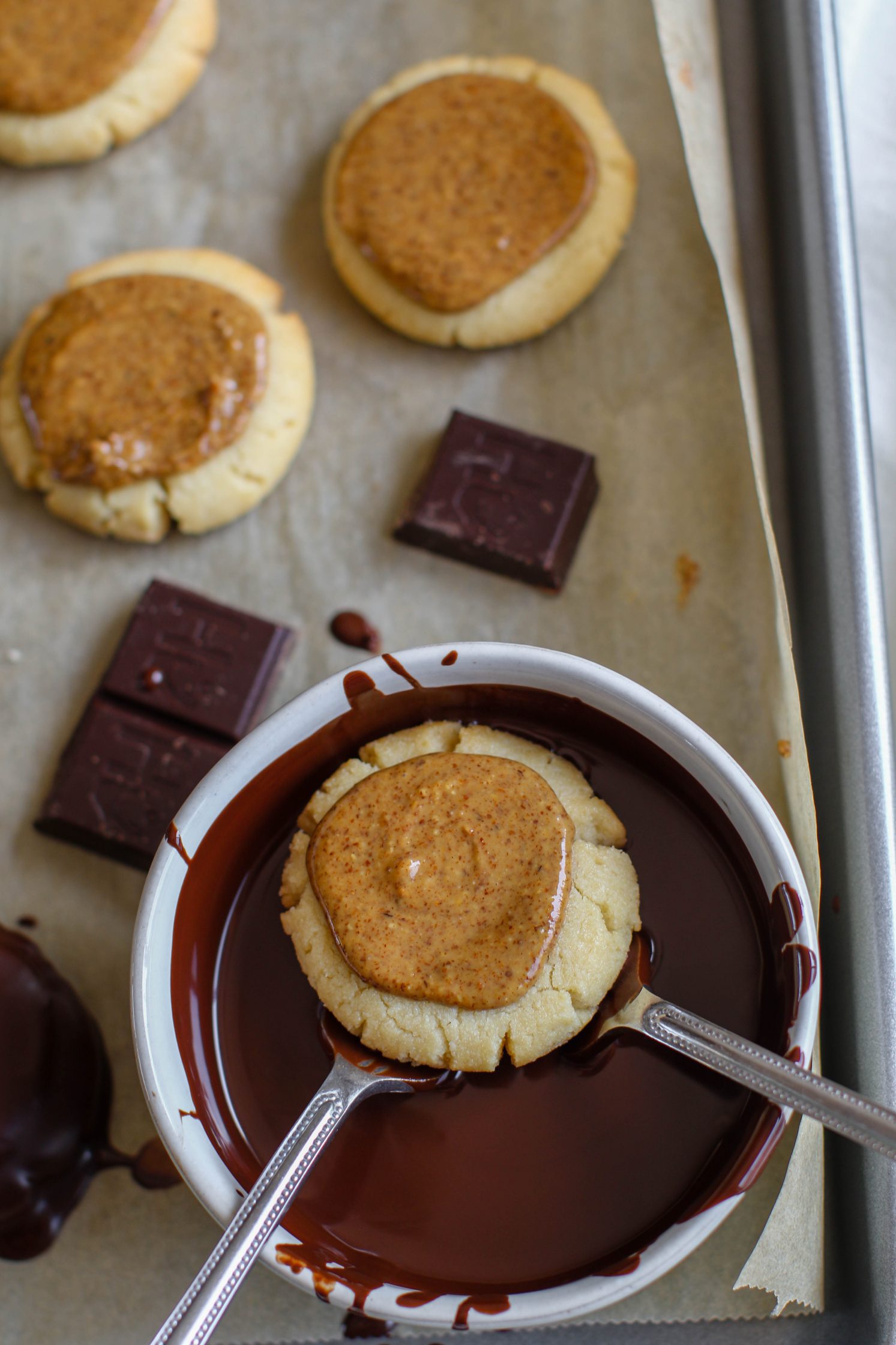 Vegan Almond Butter Tagalong dipped in bowl of melted chocolate with two forks 