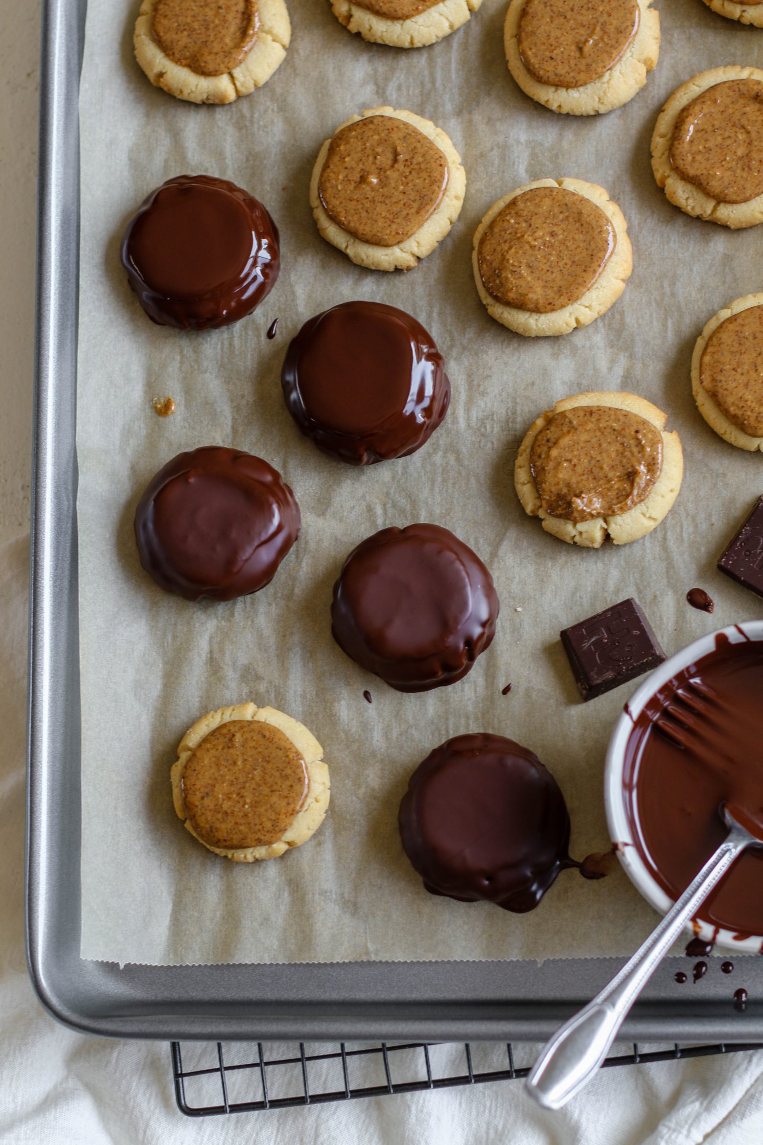 Vegan Almond Butter Tagalongs coated in melted chocolate on parchment lined baking sheet