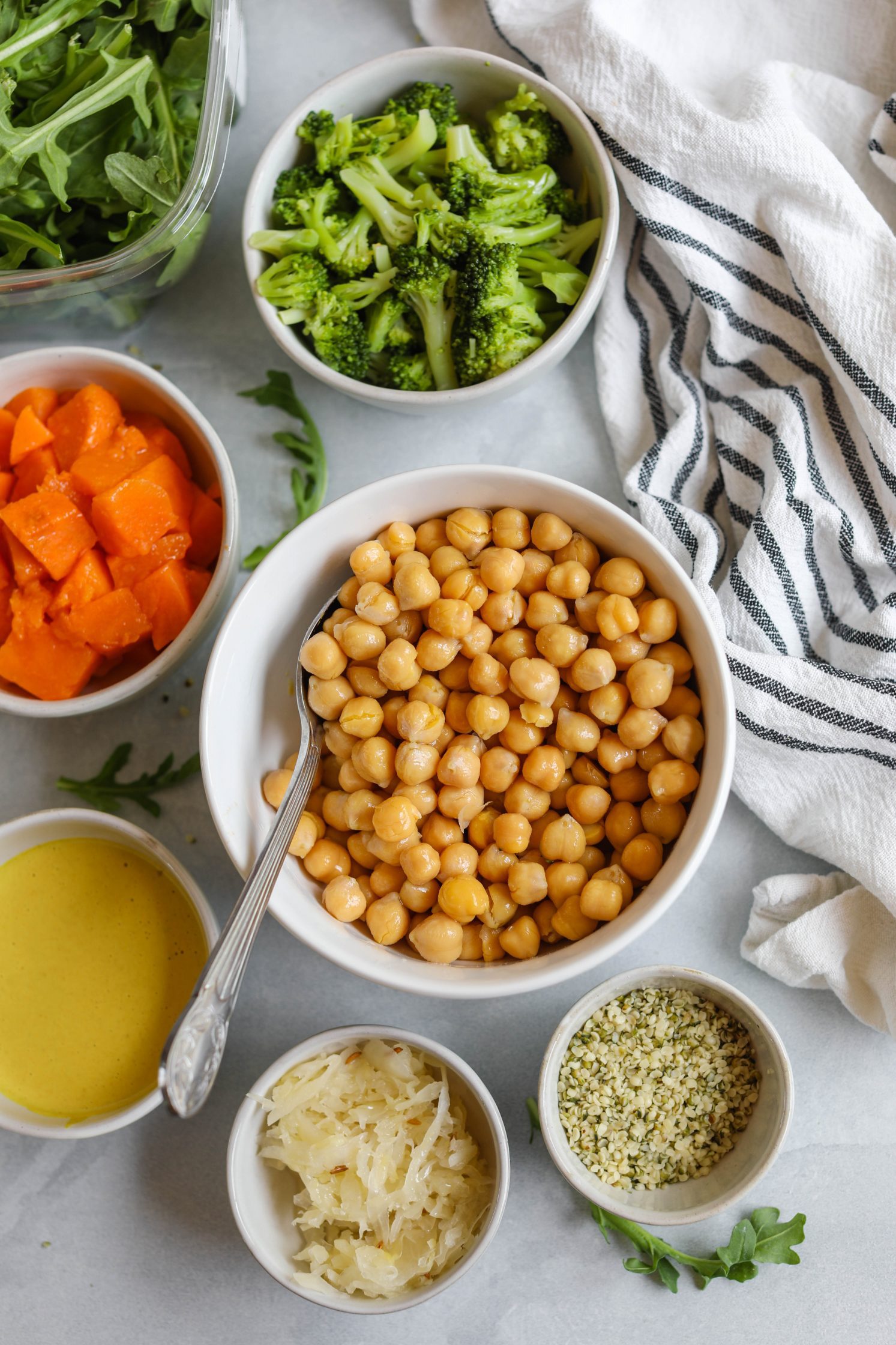 chickpeas, steamed broccoli, steamed sweet potatoes, sauerkraut, hemp hearts, and arugula in bowls by Flora & Vino
