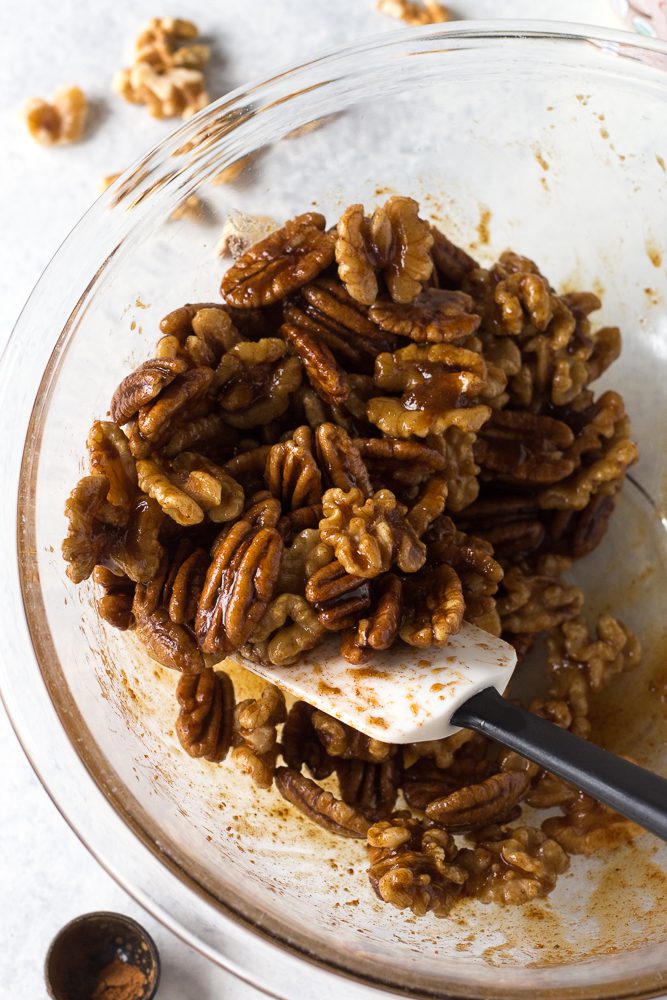 nuts coated with cinnamon and maple syrup in a bowl with a spatula by Flora & Vino