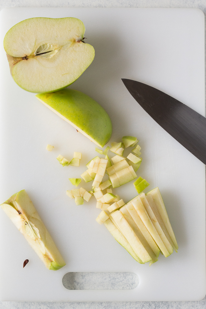 green apples diced on cutting board with knife by Flora & Vino