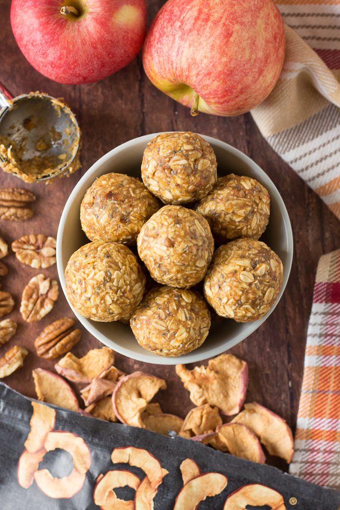 Pumpkin Apple Bliss Balls in bowl with apples, pecans, and apple chips by Flora & Vino