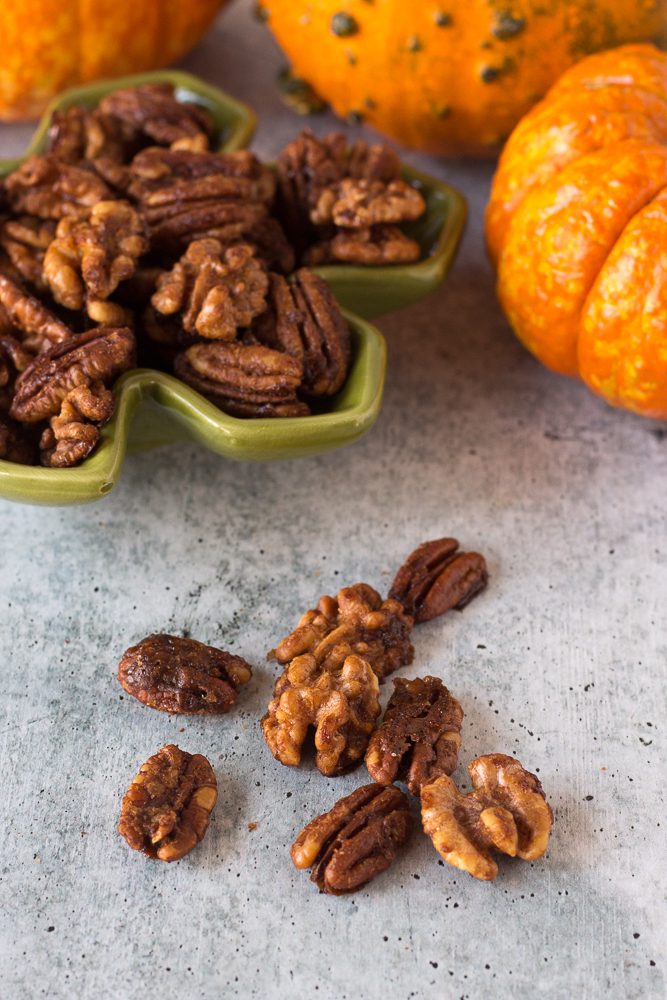 Easy Maple Spiced Nuts served in a bowl surrounded by pumpkins by Flora & Vino