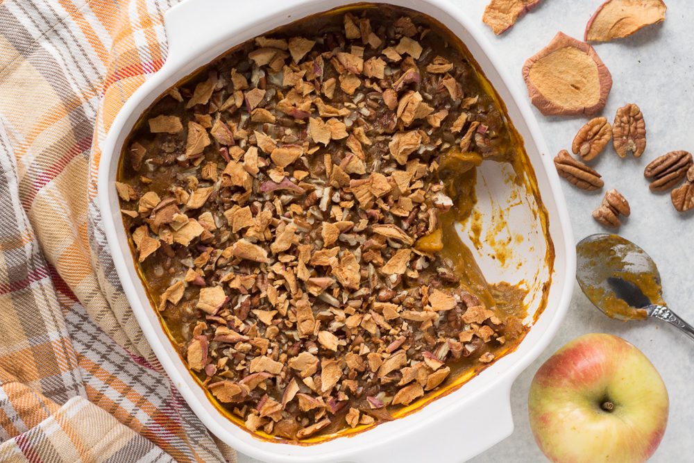 Pumpkin Apple Bake served in casserole dish with metal spoon topped with apple chips 