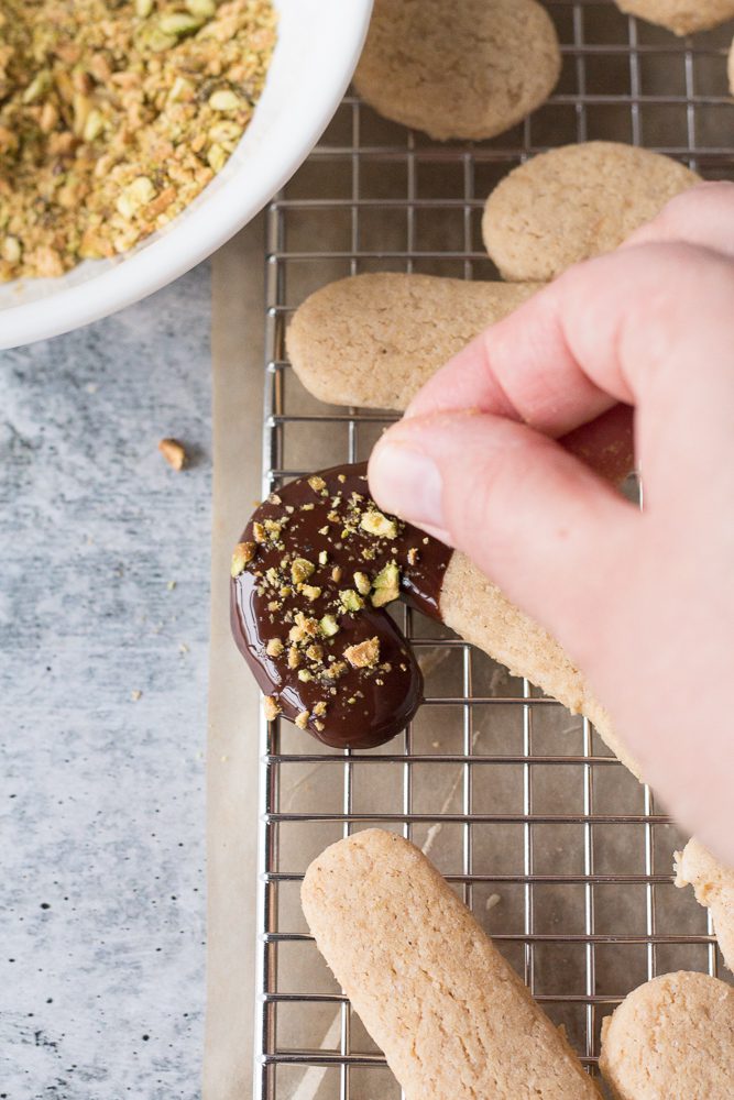adding crushed pistachios to baked vegan sugar cookies by Flora & Vino 