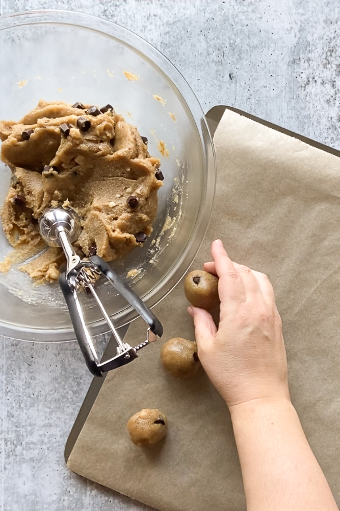 cookie batter mixed in a bowl and rolling balls on parchment paper by Flora & Vino
