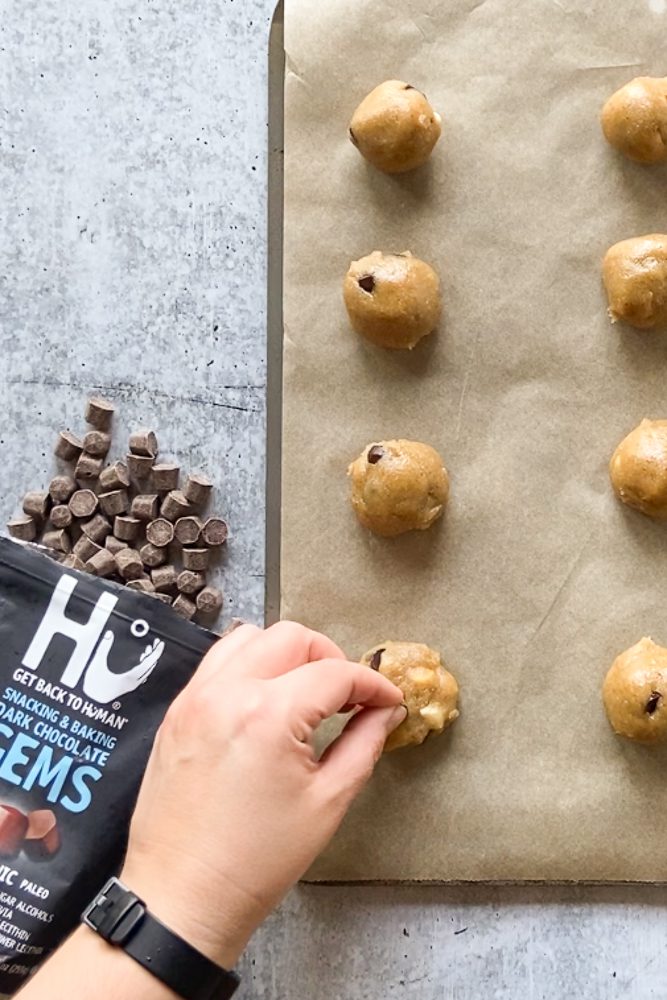 Tahini Chocolate Chip Macademia Nut Cookies rolled into balls on parchment paper lined baking sheet by Flora & Vino