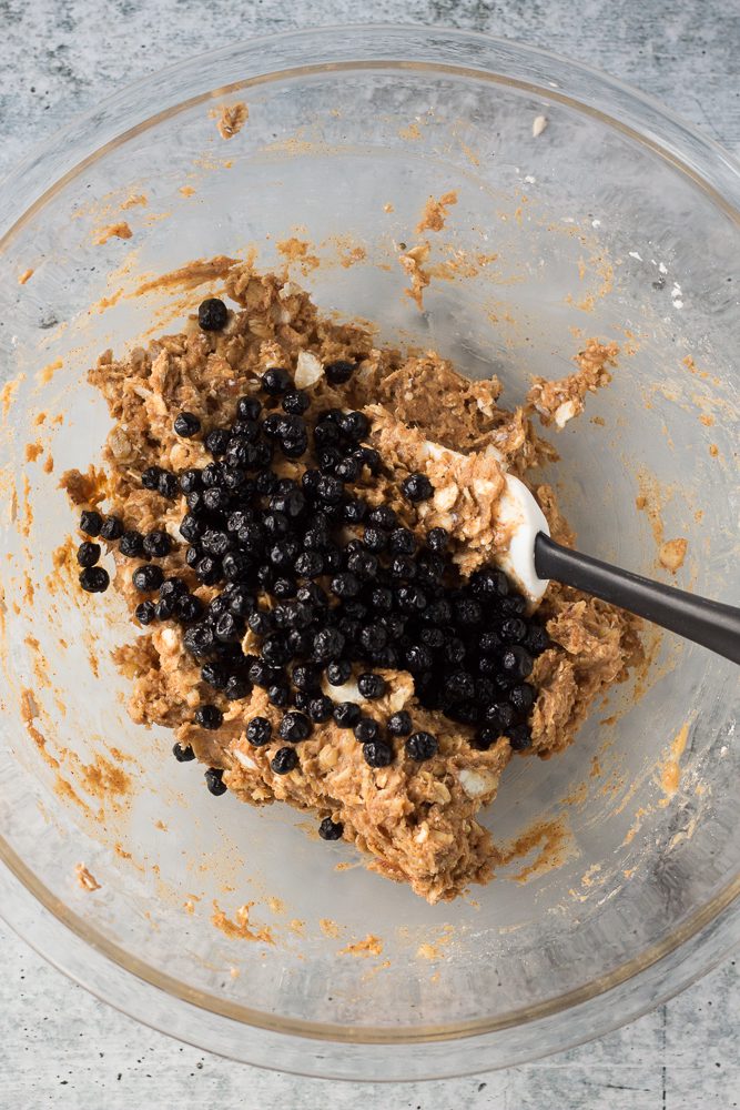 Almond Protein Cookie batter in a bowl with dried blueberries and a spatula by Flora & Vino