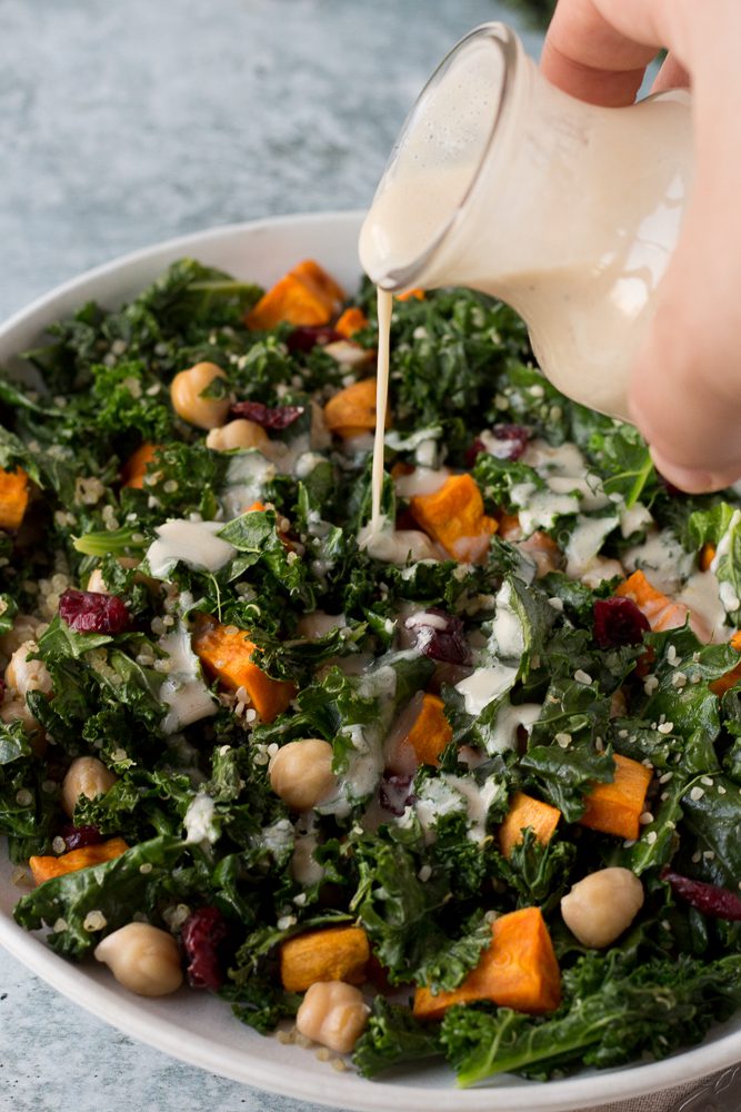 Warm Kale Quinoa Bowl with Citrus Tahini dressing poured on by Flora & Vino