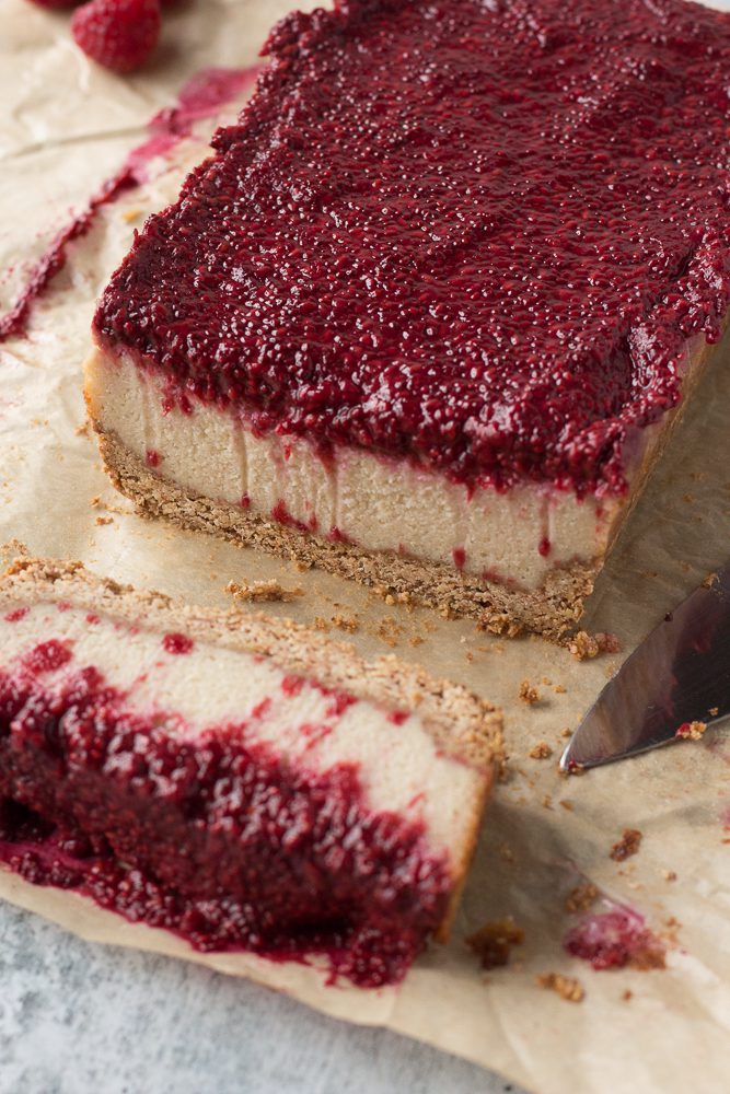 Vegan Raspberry Cheesecake sliced on parchment paper by Flora & Vino 