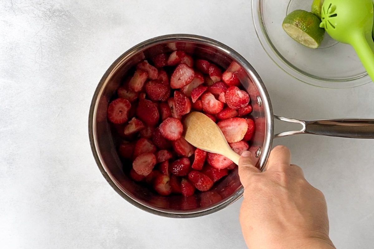 frozen strawberries in pot with wooden spoon 