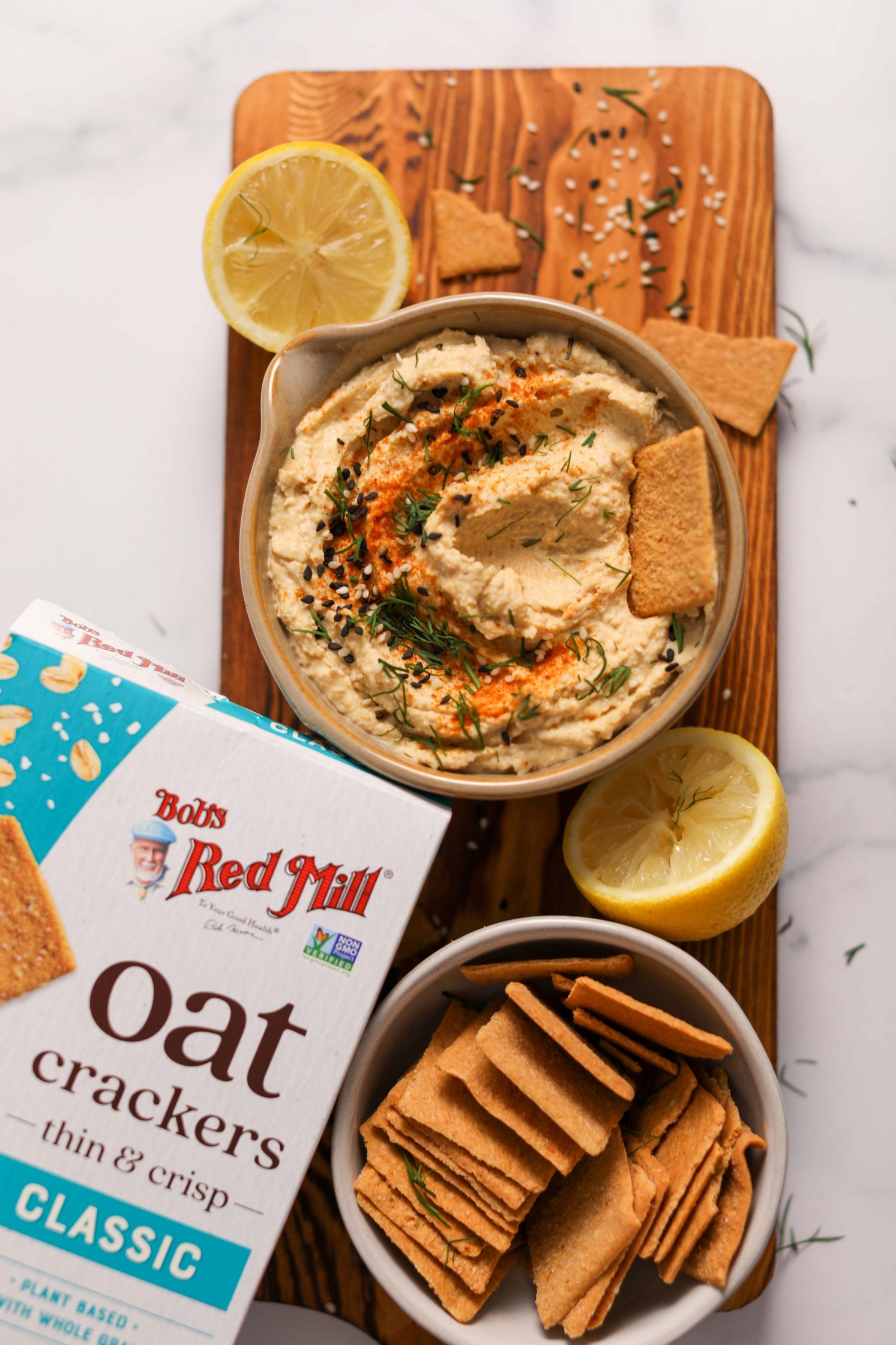 The Best Oil-Free served in ceramic bowl on wooden board with two lemon halves on the side and bowl of crackers