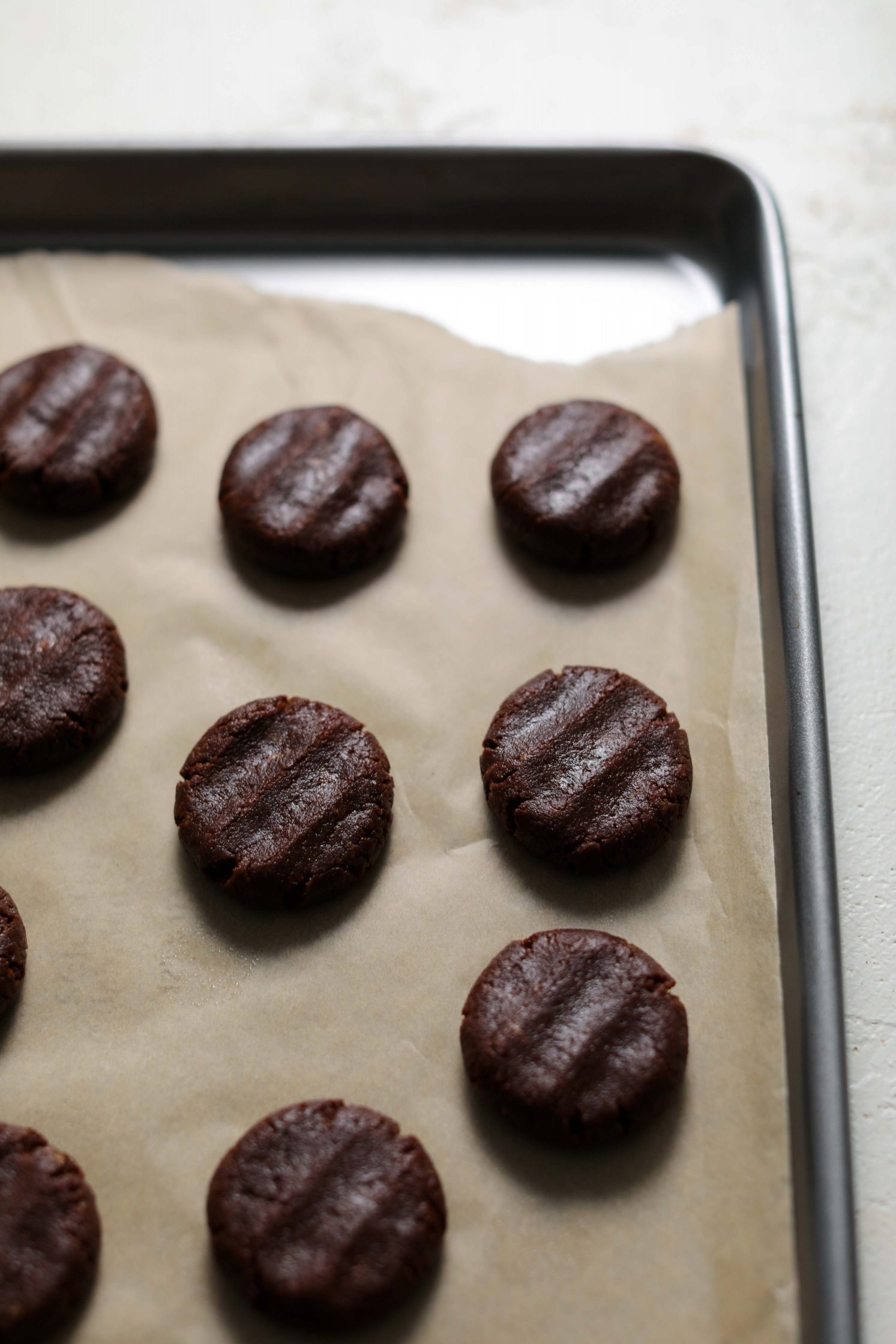raw chocolate cookies on parchment lined baking sheet by Flora & Vino 