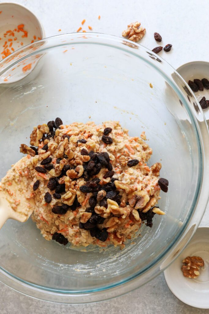 Carrot Cake Almond Flour Muffin batter with walnuts and raisins on top with spatula 