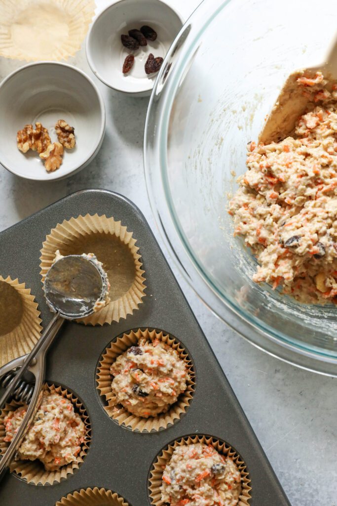 Carrot Cake Almond Flour Muffin batter scooped into parchment lined muffin tins