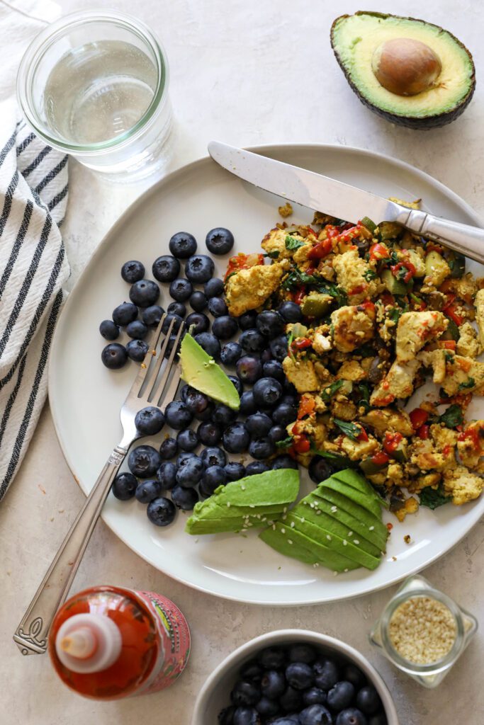 Easy Tofu Scramble Plate with blueberries and avocado and sriracha by Flora & Vino
