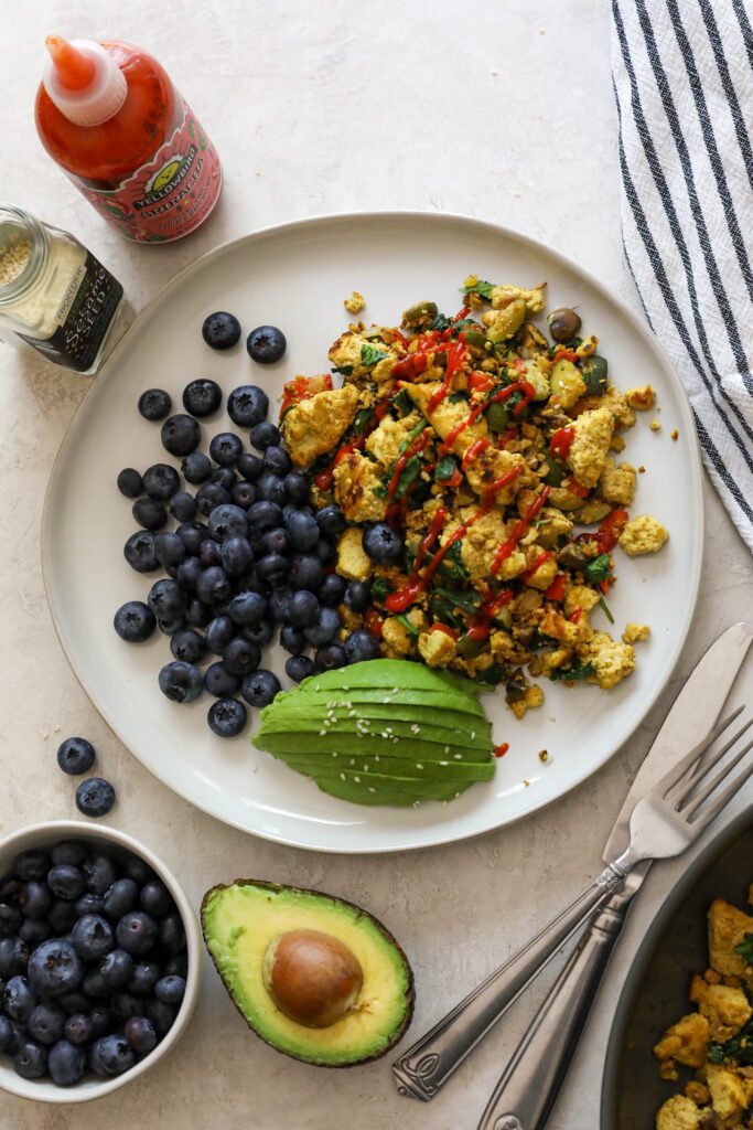 Easy Tofu Scramble Plate served with blueberries and avocado and sriracha by Flora & Vino