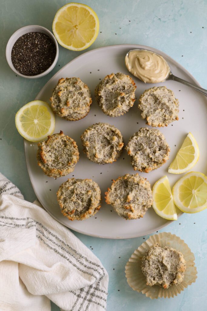 Lemon Cashew Chia Seed Muffins served on a plate with lemon and spoon with cashew butter and a bowl of chia seeds and a white towel with blue stripes by Flora & Vino
