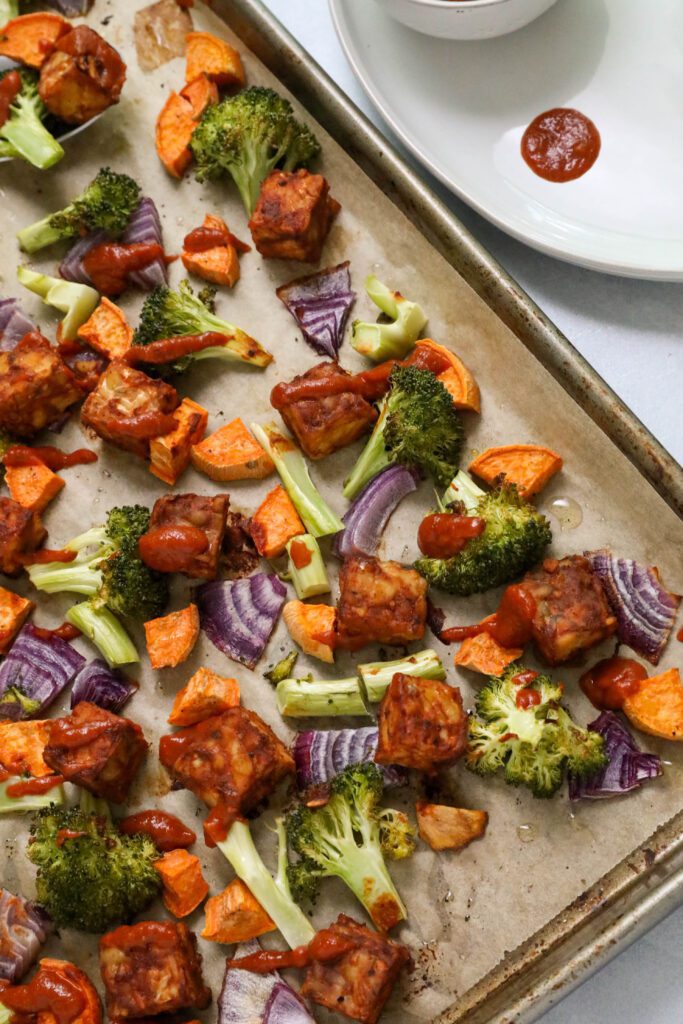 BBQ tempeh and vegetables baked on parchment lined baking sheet