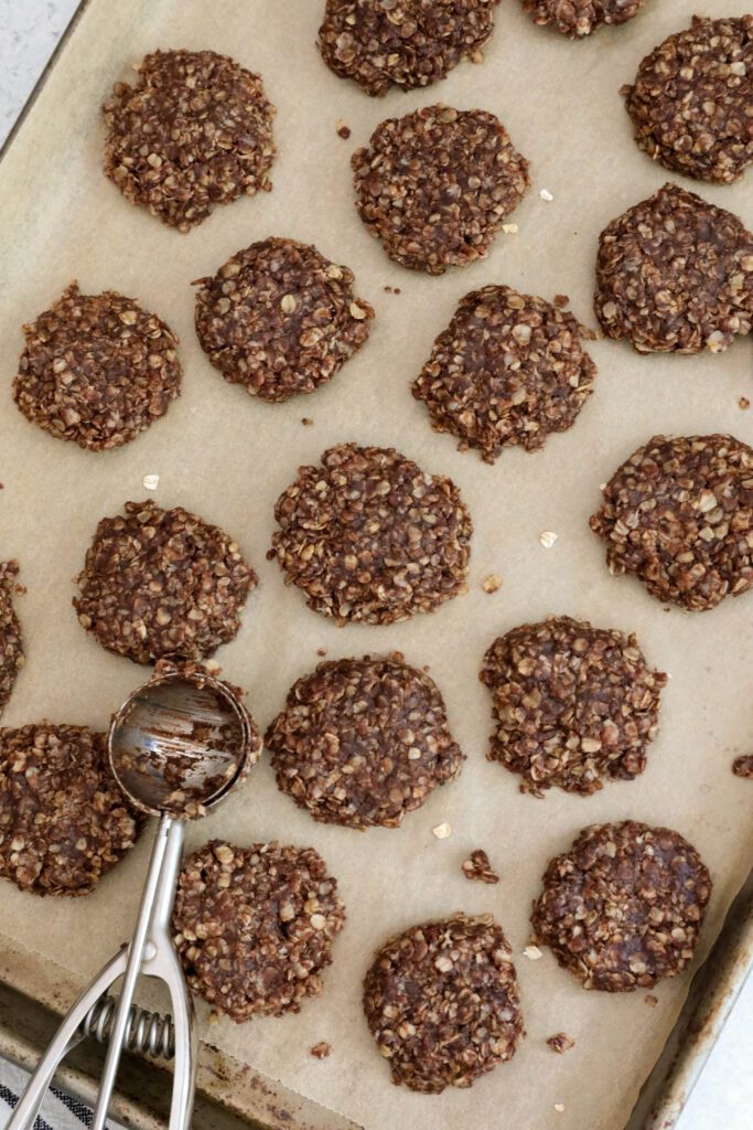 Chocolate Tahini No-Bake Cookies formed on parchment lined baking sheet with a cookie scoop by Flora & Vino