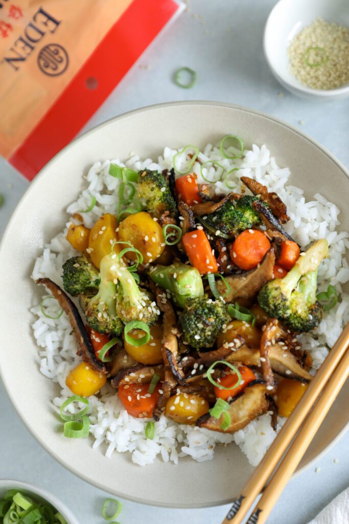 Sesame Shiitake & Broccoli Stir-Fry served over jasmine rice with green onion and sesame seeds on top and chopsticks on the side by Flora & Vino