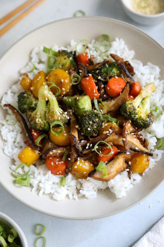 Sesame Shiitake & Broccoli Stir-Fry served over jasmine rice with green onion and sesame seeds on top and chopsticks on the side by Flora & Vino